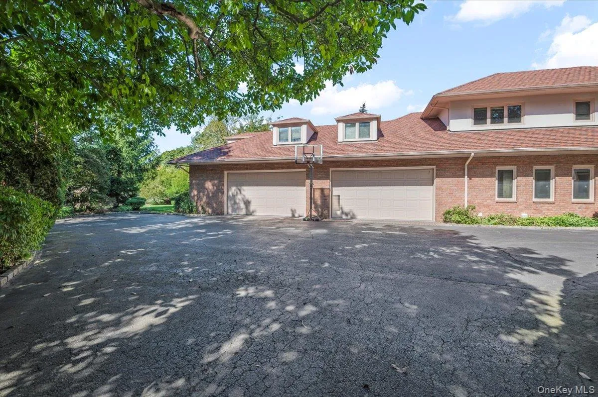 Traditional home featuring asphalt driveway, brick siding, and a garage Traditional home featuring asphalt driveway, brick siding, and a garage
