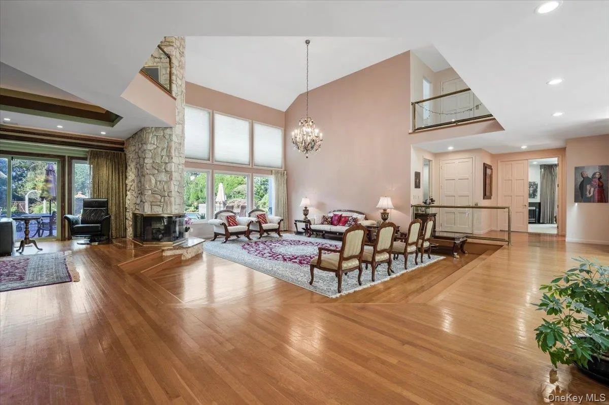 Living room with recessed lighting, wood-type flooring, plenty of natural light, high vaulted ceiling, and a chandelier Living room with recessed lighting, wood-type flooring, plenty of natural light, high vaulted ceiling, and a chandelier
