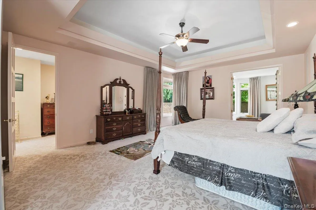 Bedroom with a raised ceiling, carpet flooring, and multiple windows Bedroom with a raised ceiling, carpet flooring, and multiple windows