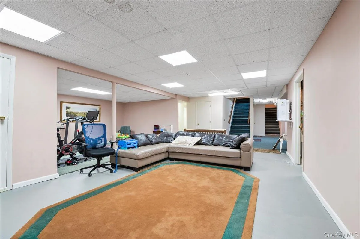Living area with stairs, finished concrete floors, and a paneled ceiling Living area with stairs, finished concrete floors, and a paneled ceiling