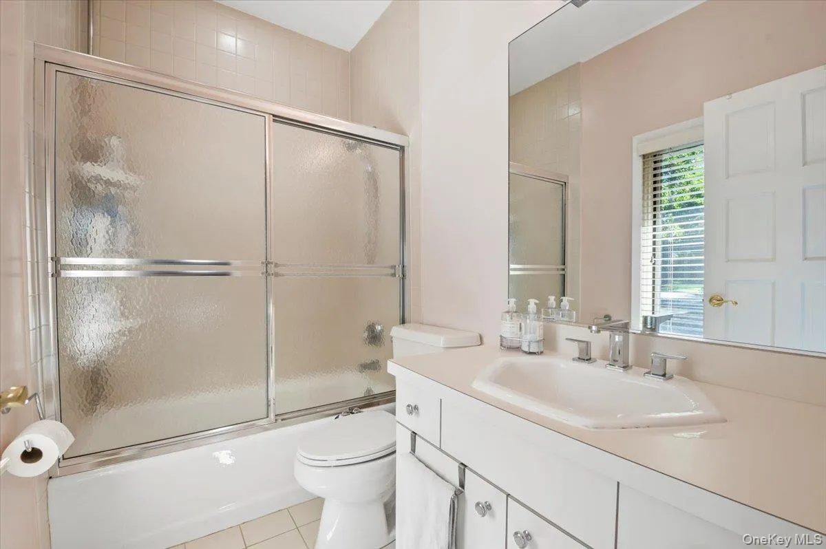 Bathroom with enclosed tub / shower combo, vanity, and light tile patterned flooring Bathroom with enclosed tub / shower combo, vanity, and light tile patterned flooring
