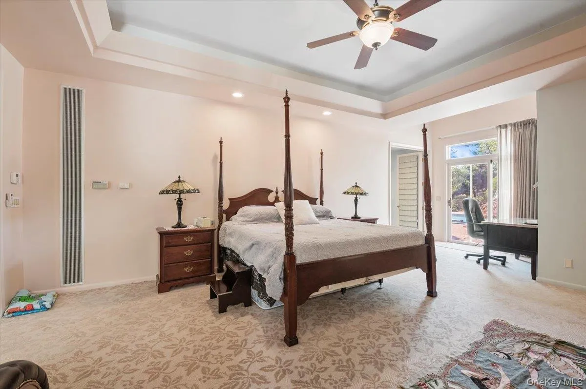 Bedroom featuring a tray ceiling, light carpet, an office area, access to exterior, and ceiling fan Bedroom featuring a tray ceiling, light carpet, an office area, access to exterior, and ceiling fan