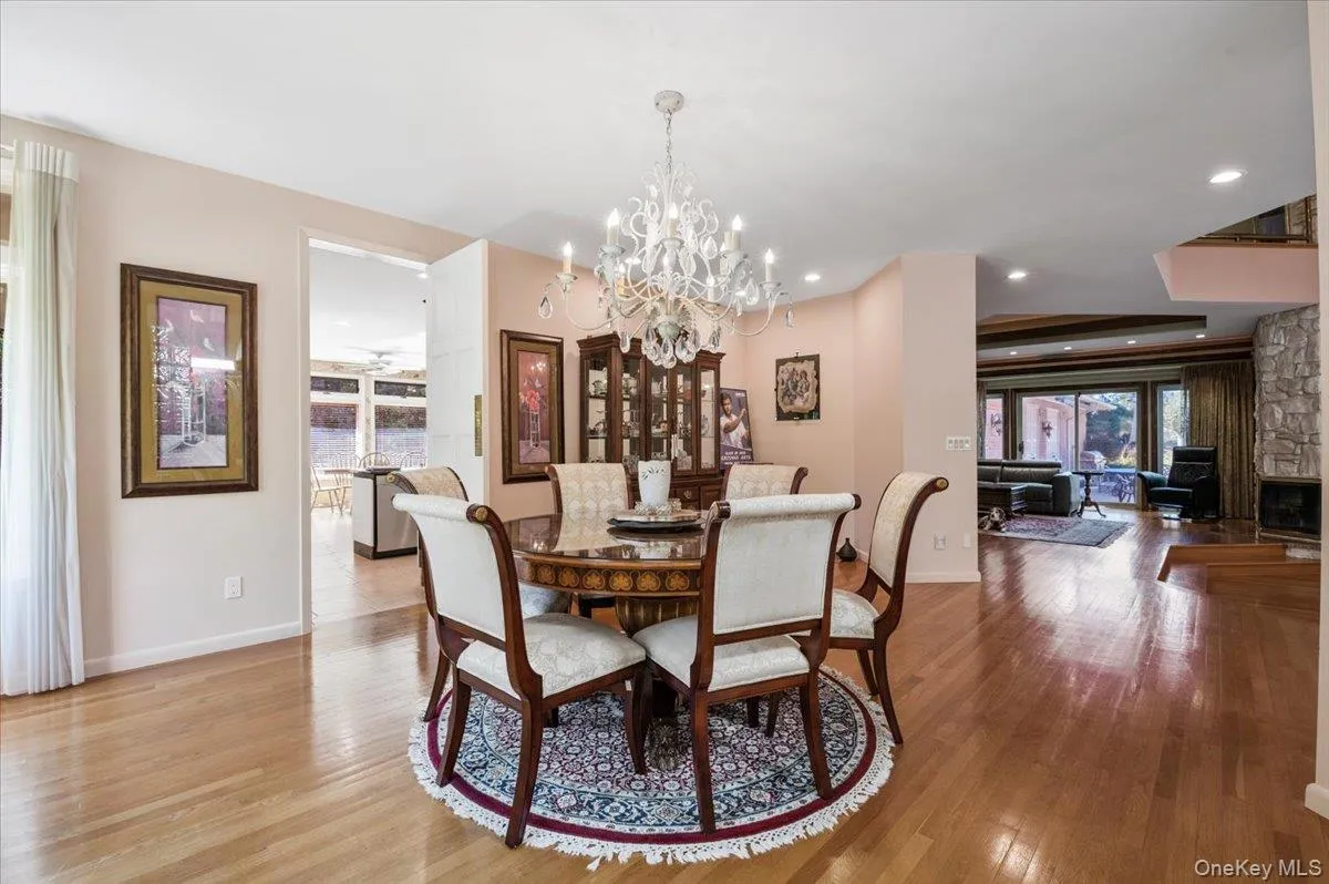 Dining area featuring light wood-type flooring, plenty of natural light, a chandelier, a stone fireplace, and recessed lighting Dining area featuring light wood-type flooring, plenty of natural light, a chandelier, a stone fireplace, and recessed lighting
