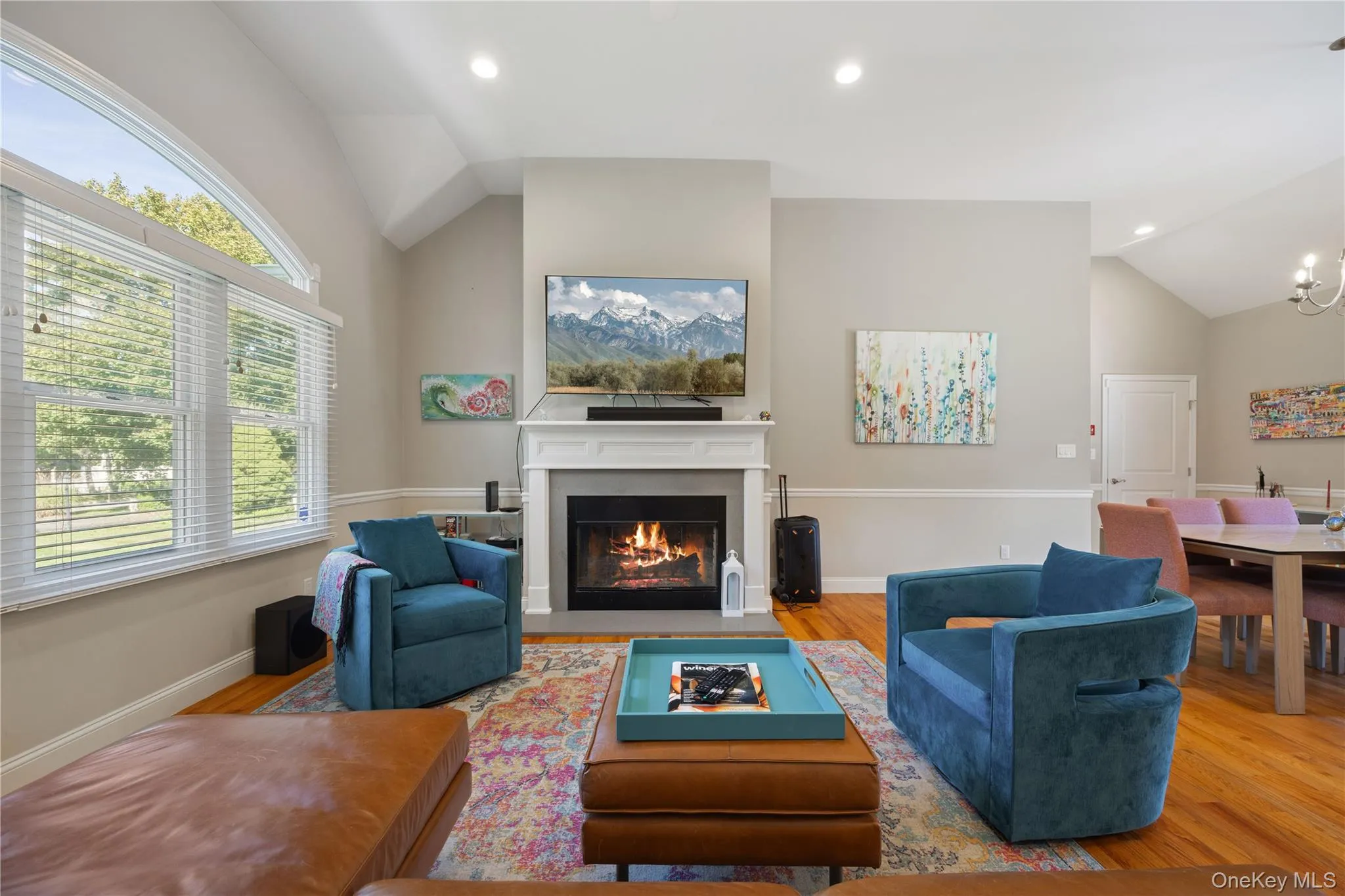 Living area featuring lofted ceiling, a fireplace with flush hearth, wood finished floors, a chandelier, and recessed lighting Living area featuring lofted ceiling, a fireplace with flush hearth, wood finished floors, a chandelier, and recessed lighting