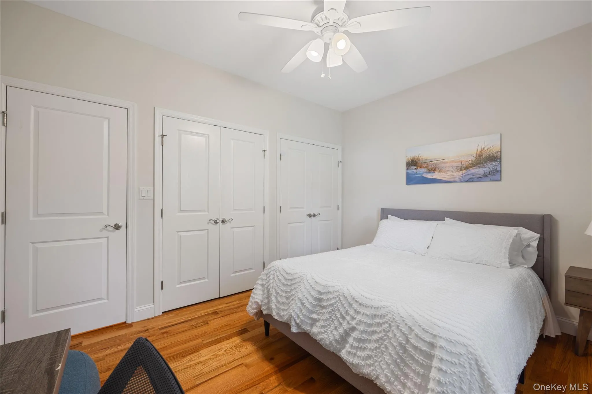 Bedroom with light wood-style flooring, a ceiling fan, and two closets Bedroom with light wood-style flooring, a ceiling fan, and two closets