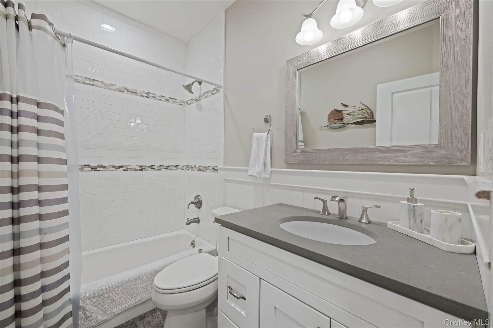 Bathroom with shower / tub combo, vanity, and wainscoting Bathroom with shower / tub combo, vanity, and wainscoting