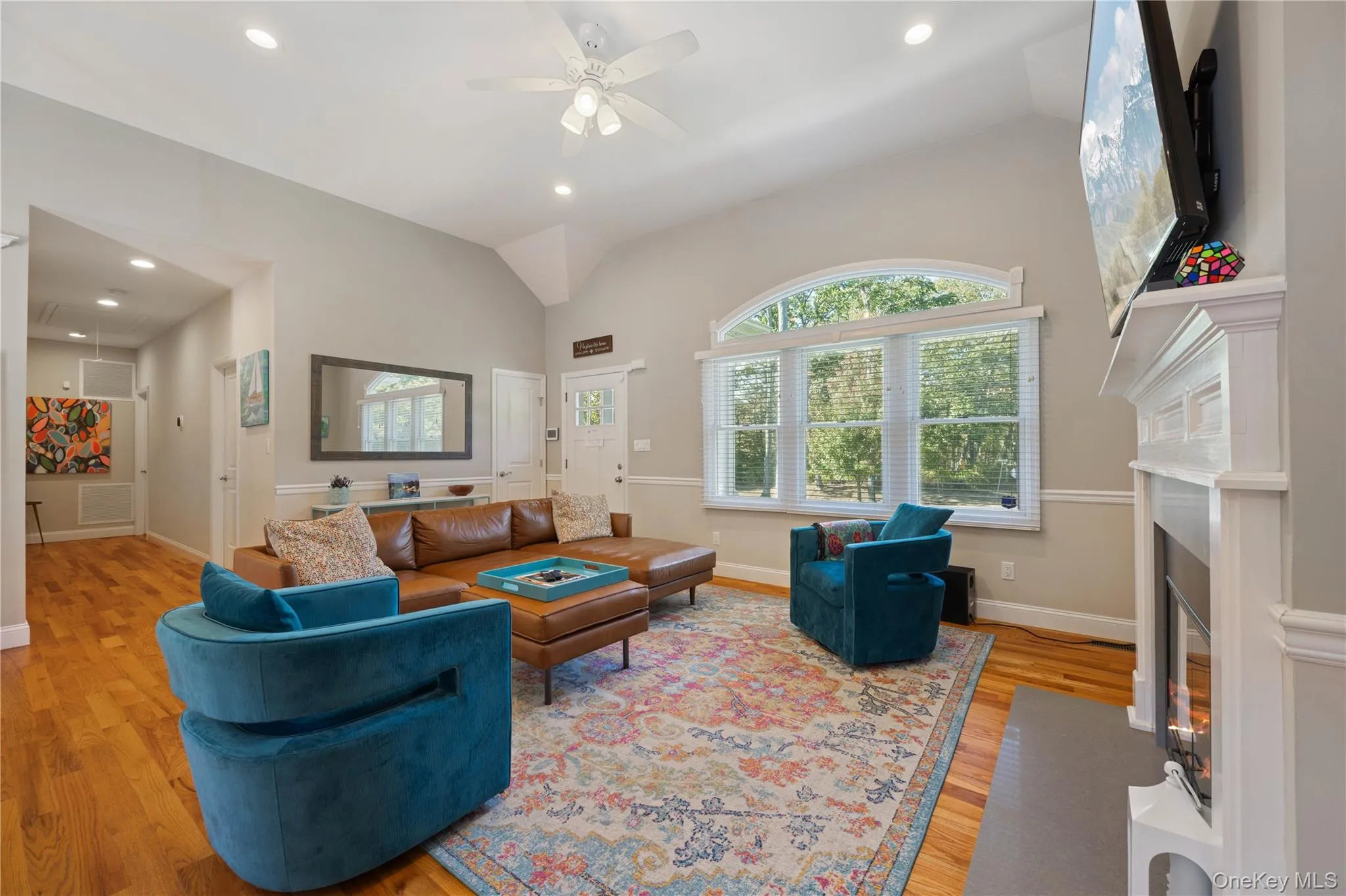 Living room featuring light wood finished floors, vaulted ceiling, a fireplace with flush hearth, recessed lighting, and ceiling fan Living room featuring light wood finished floors, vaulted ceiling, a fireplace with flush hearth, recessed lighting, and ceiling fan