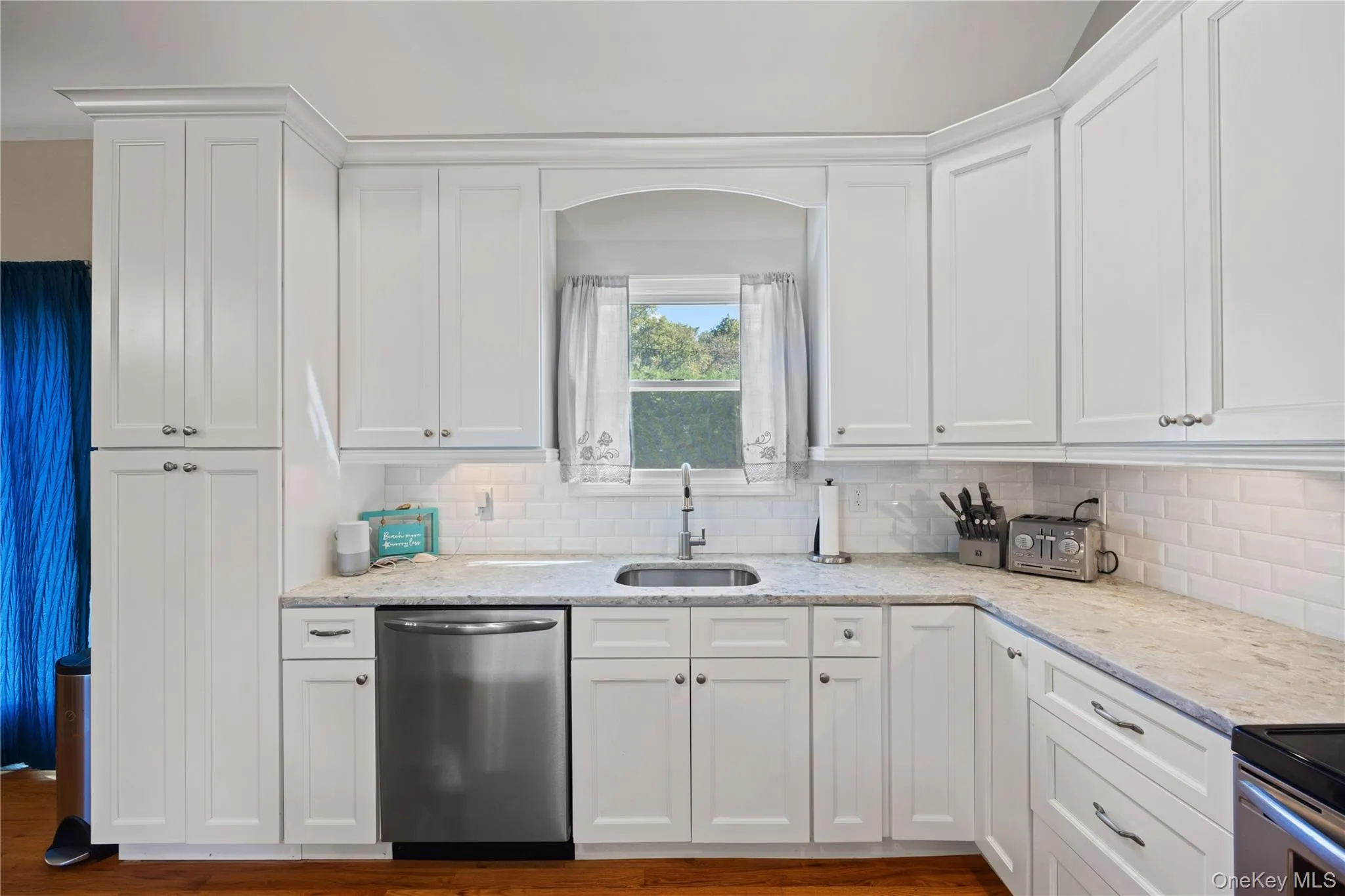 Kitchen with white cabinets, light stone countertops, and stainless steel appliances Kitchen with white cabinets, light stone countertops, and stainless steel appliances