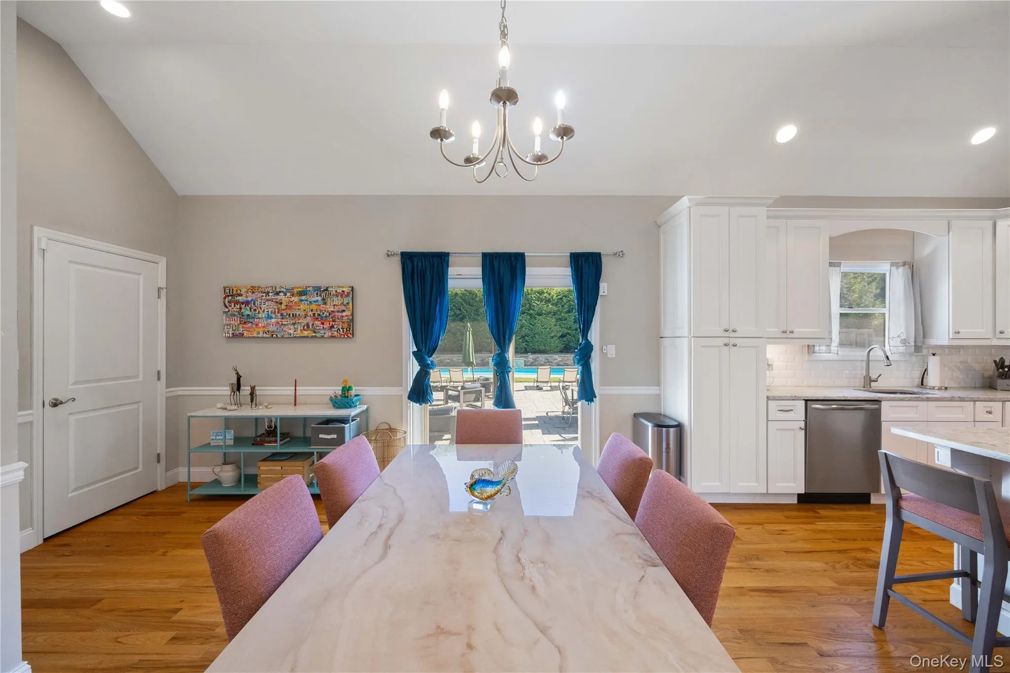 Dining room with recessed lighting, light wood finished floors, lofted ceiling, and a chandelier Dining room with recessed lighting, light wood finished floors, lofted ceiling, and a chandelier