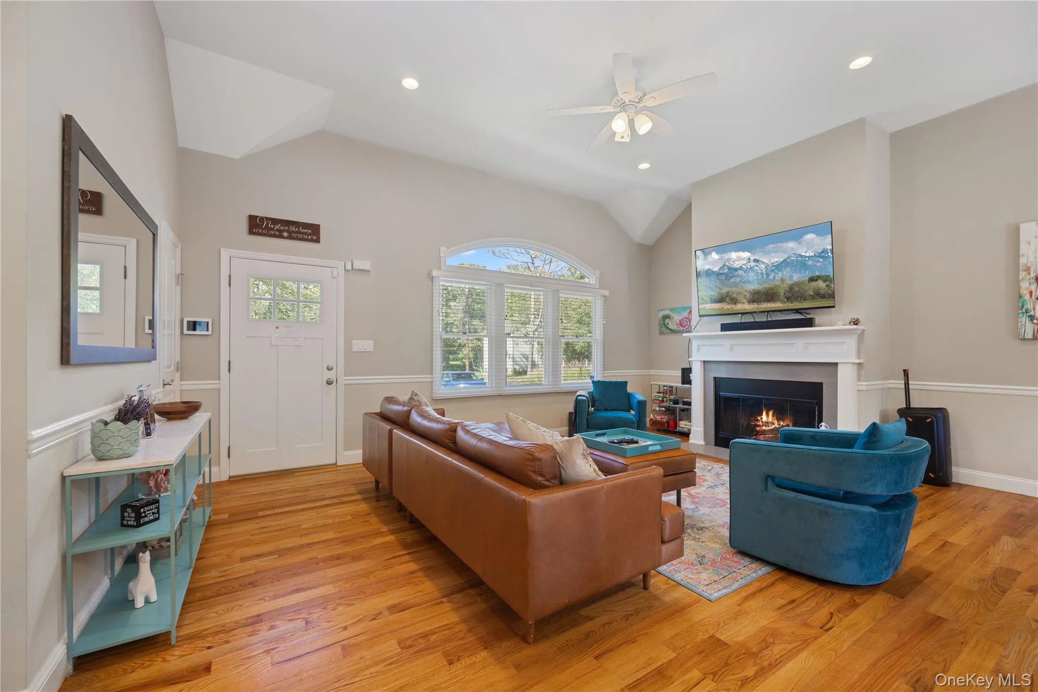 Living area featuring a glass covered fireplace, vaulted ceiling, light wood-style flooring, ceiling fan, and recessed lighting Living area featuring a glass covered fireplace, vaulted ceiling, light wood-style flooring, ceiling fan, and recessed lighting
