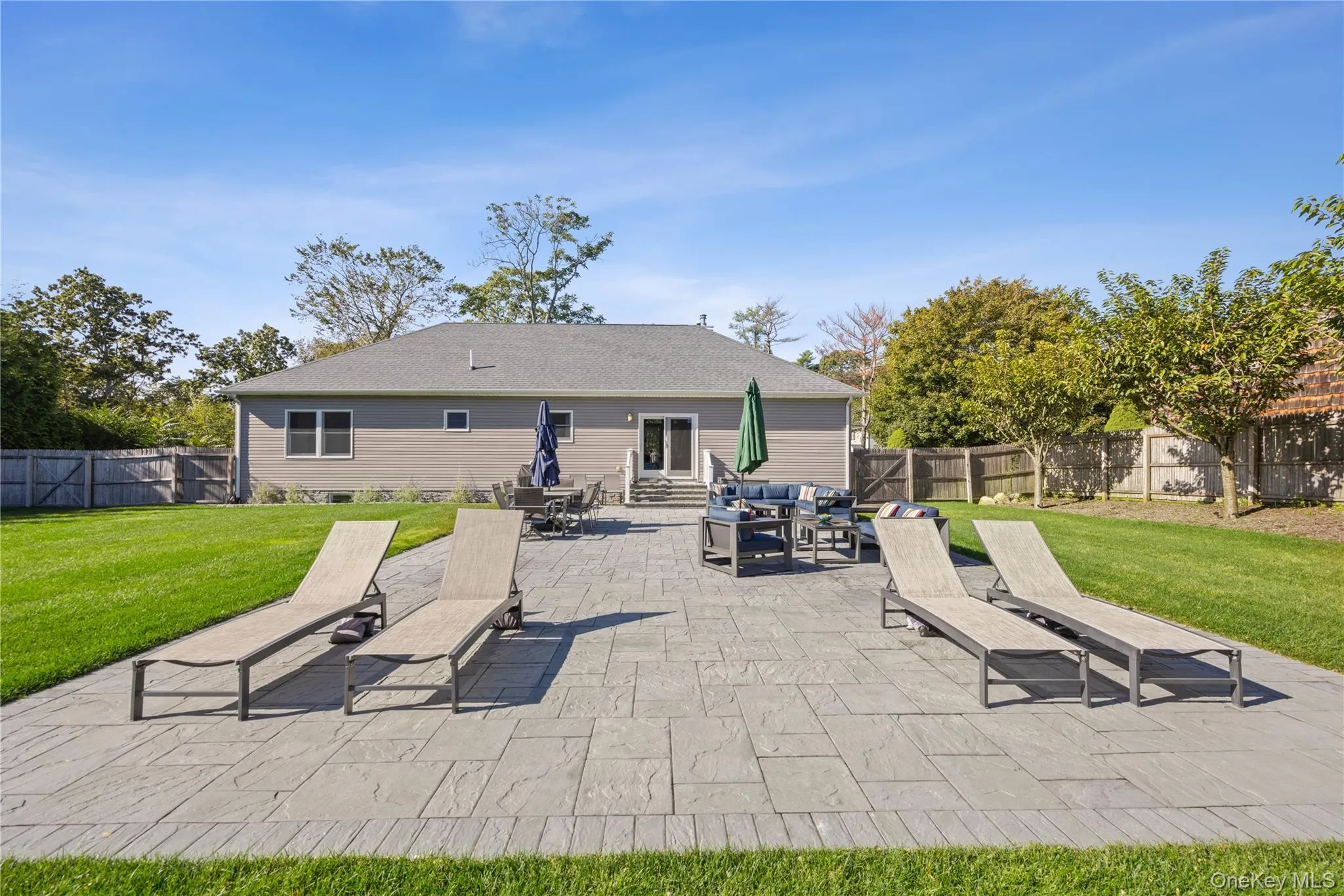 Fenced backyard with a patio, an outdoor hangout area, and entry steps Fenced backyard with a patio, an outdoor hangout area, and entry steps