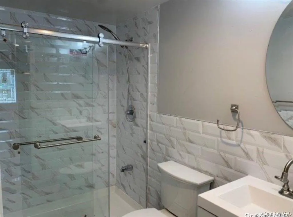 Bathroom with tile walls, a stall shower, and vanity Bathroom with tile walls, a stall shower, and vanity