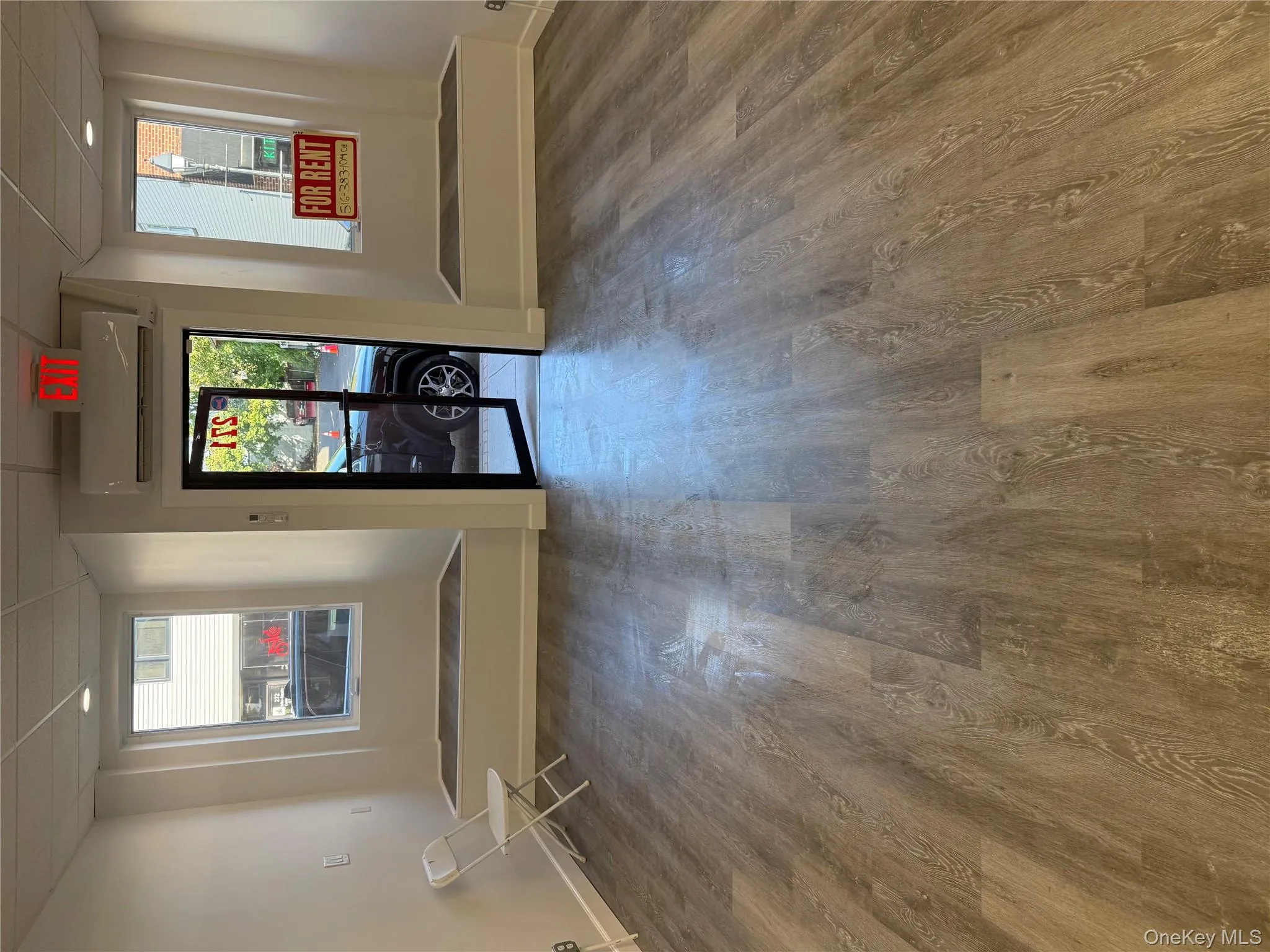 Unfurnished room with a paneled ceiling, dark wood-style flooring, and an AC wall unit Unfurnished room with a paneled ceiling, dark wood-style flooring, and an AC wall unit