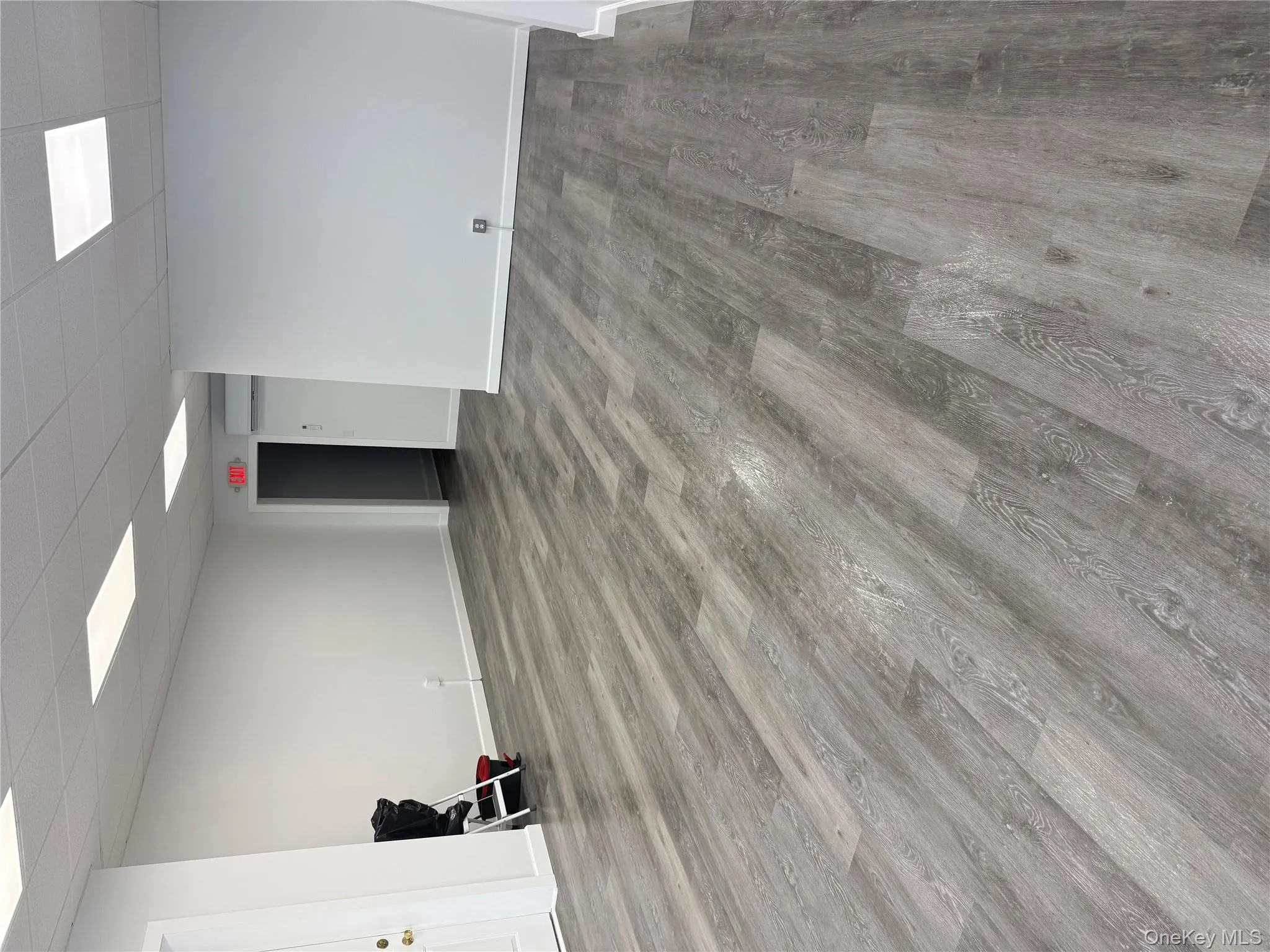 Basement with a drop ceiling, wood finished floors, and a wall unit AC Basement with a drop ceiling, wood finished floors, and a wall unit AC