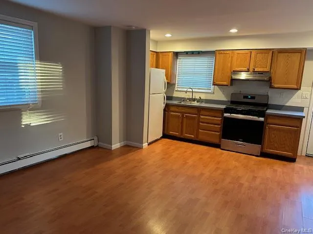 Kitchen featuring stainless steel range oven, brown cabinets, light wood finished floors, freestanding refrigerator, and tasteful backsplash Kitchen featuring stainless steel range oven, brown cabinets, light wood finished floors, freestanding refrigerator, and tasteful backsplash