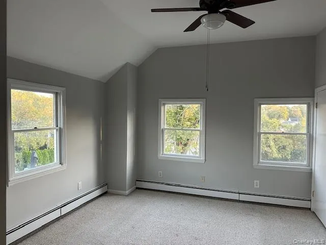 Bedroom with a baseboard radiator, light carpet, lofted ceiling, and ceiling fan Bedroom with a baseboard radiator, light carpet, lofted ceiling, and ceiling fan