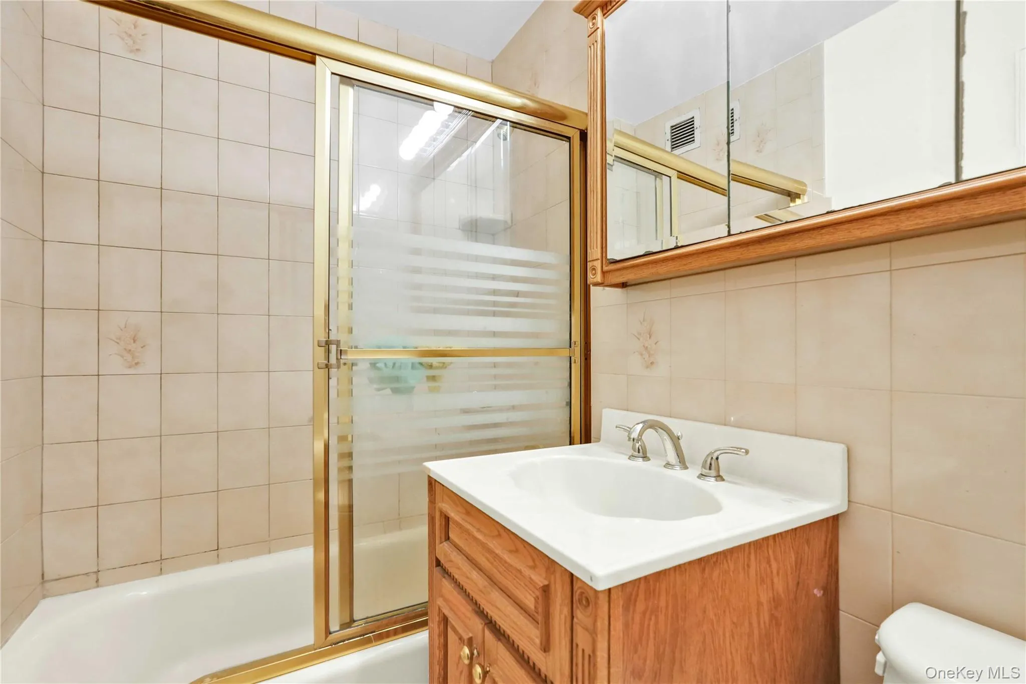 Full bathroom with shower / bath combination with glass door, tile walls, vanity, and backsplash Full bathroom with shower / bath combination with glass door, tile walls, vanity, and backsplash