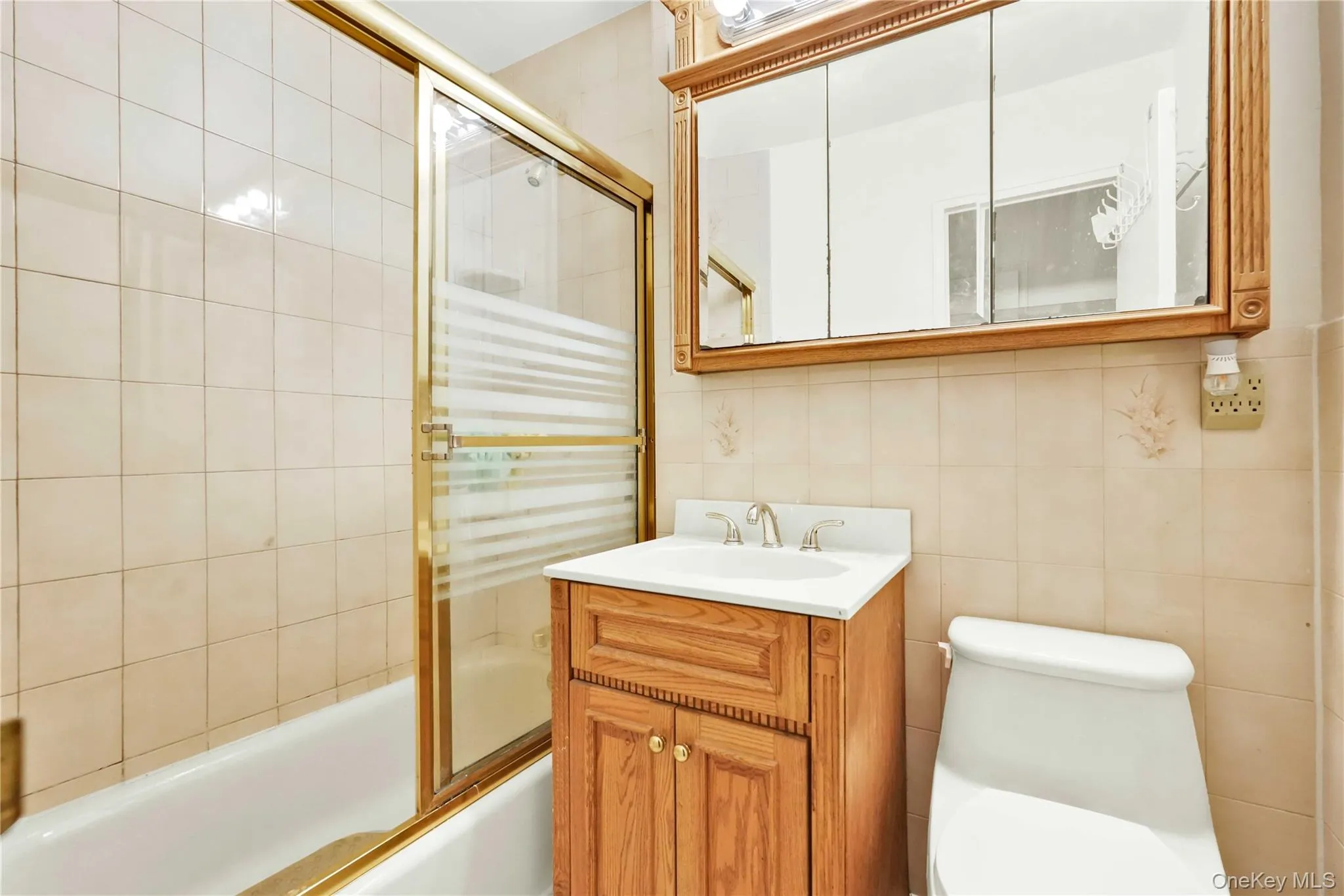 Full bathroom with shower / bath combination with glass door, vanity, and tile walls Full bathroom with shower / bath combination with glass door, vanity, and tile walls