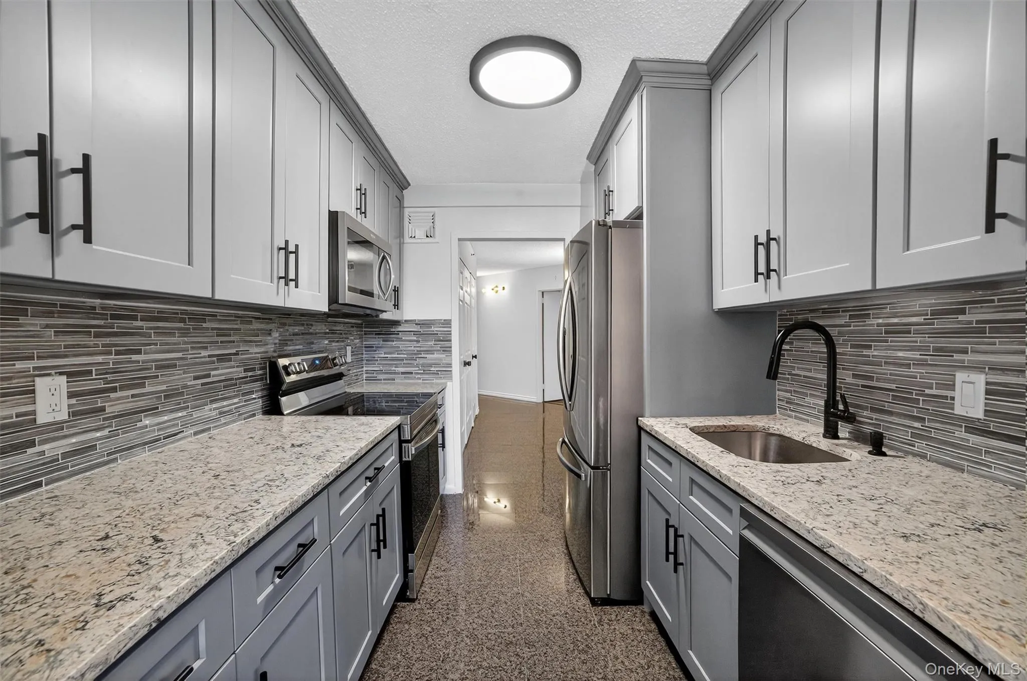 Kitchen featuring gray cabinetry, backsplash, and a textured ceiling Kitchen featuring gray cabinetry, backsplash, and a textured ceiling