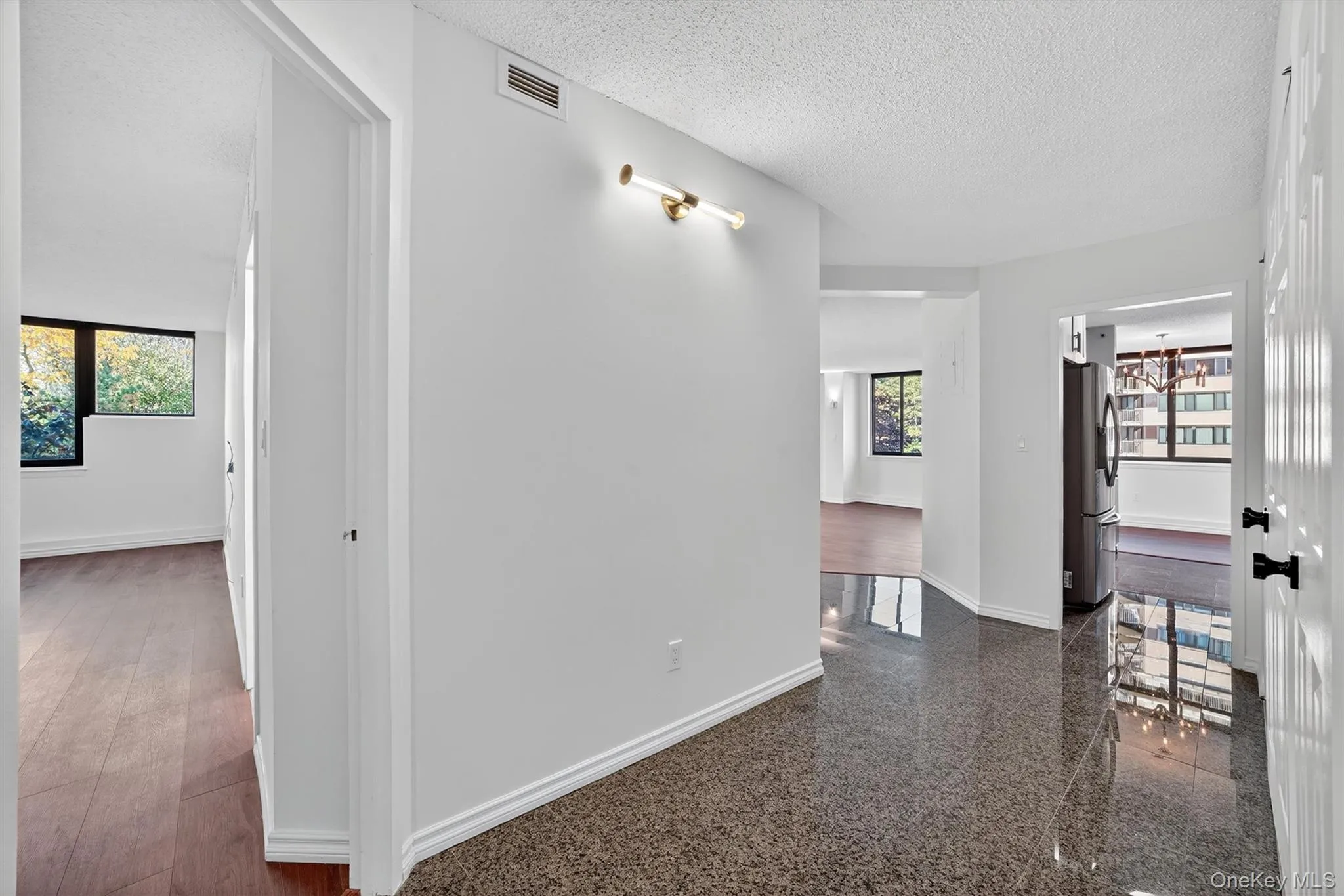 Hallway with a textured ceiling, a chandelier, and granite floors Hallway with a textured ceiling, a chandelier, and granite floors