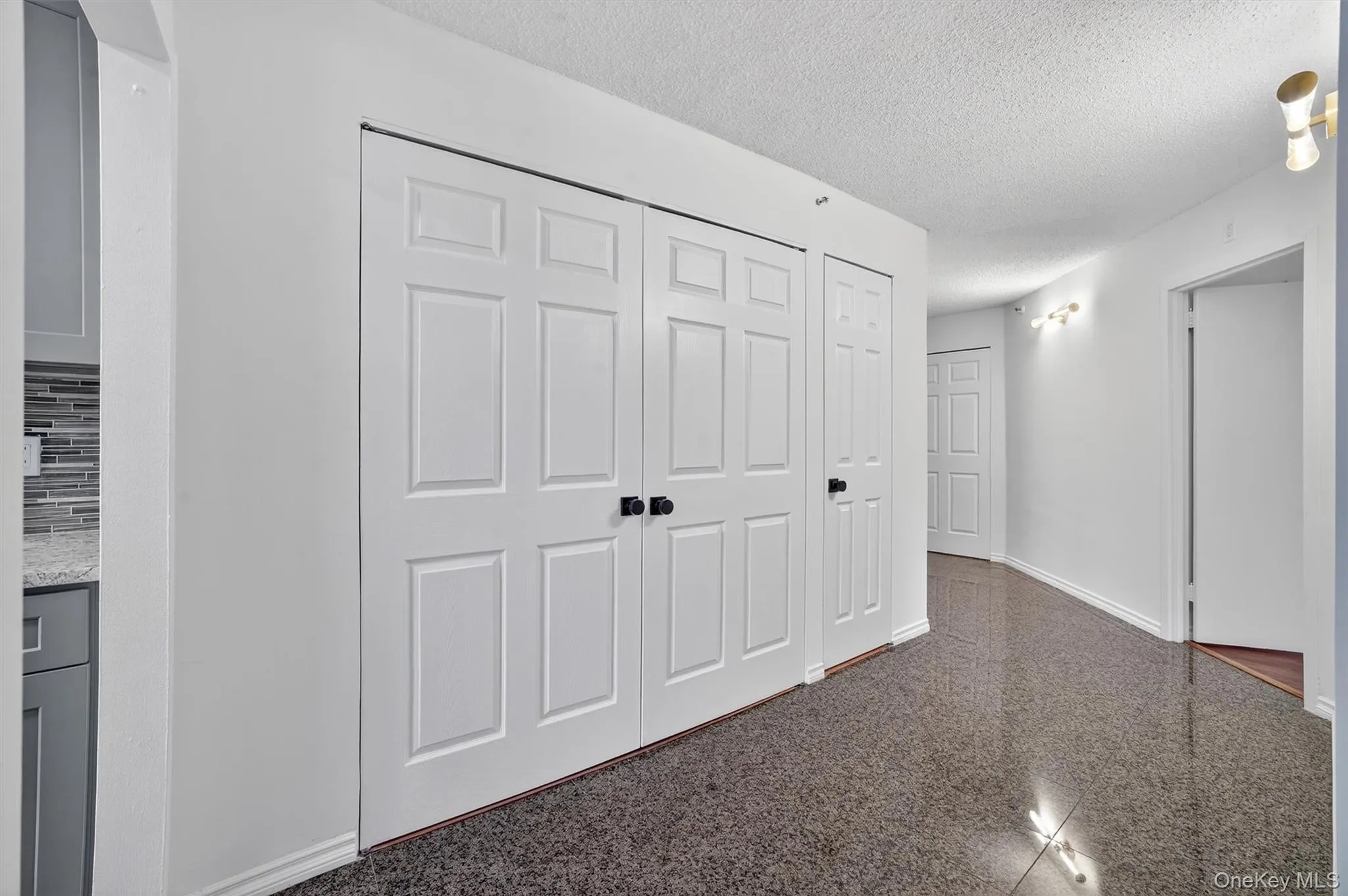 Hall featuring a textured ceiling and granite tiled floors Hall featuring a textured ceiling and granite tiled floors