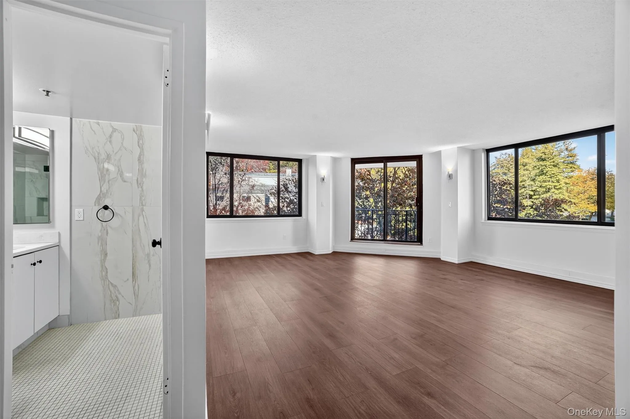 Unfurnished living room featuring wood finished floors and a textured ceiling Unfurnished living room featuring wood finished floors and a textured ceiling