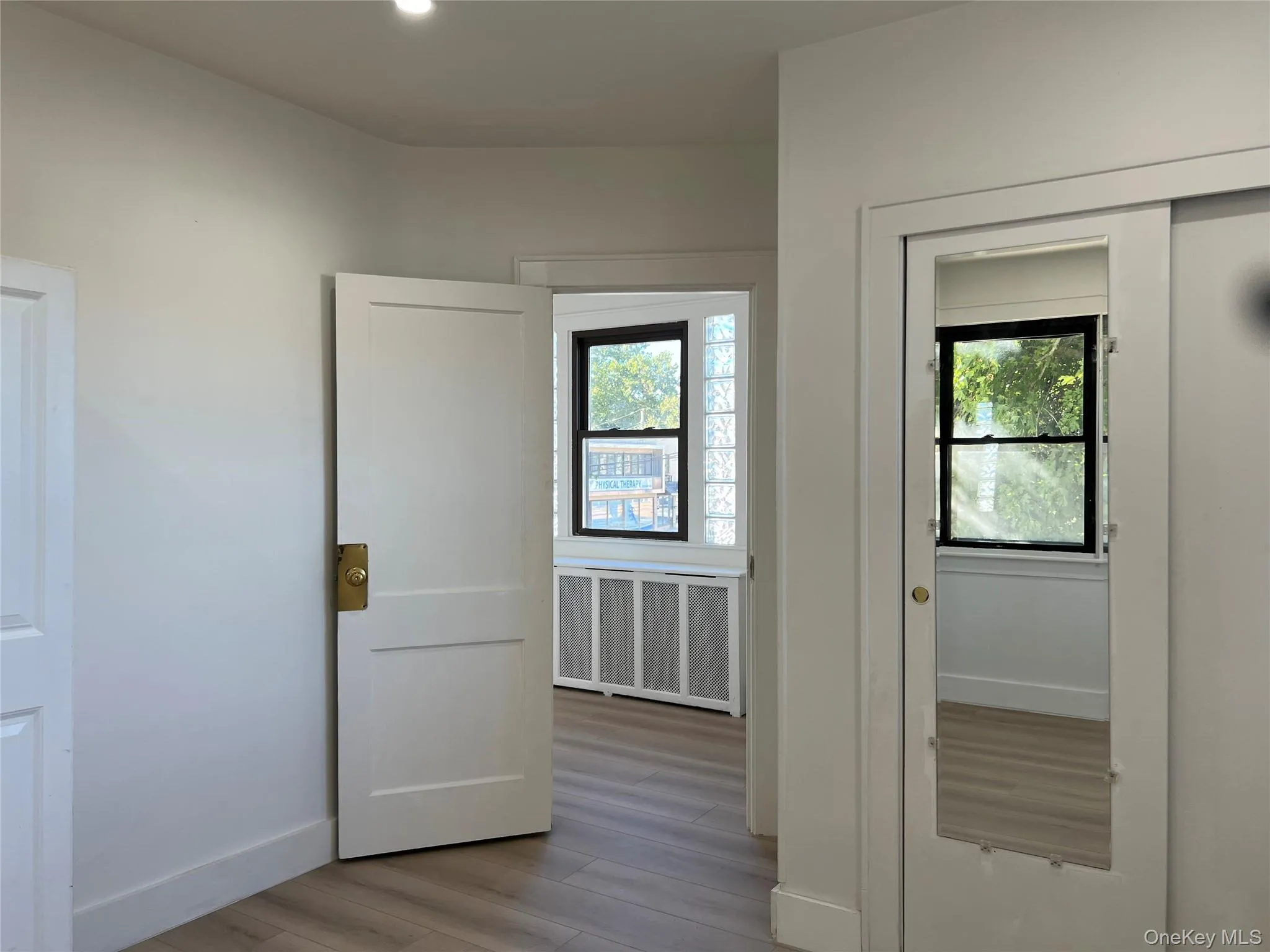 Hall featuring light wood finished floors, radiator heating unit, and recessed lighting Hall featuring light wood finished floors, radiator heating unit, and recessed lighting