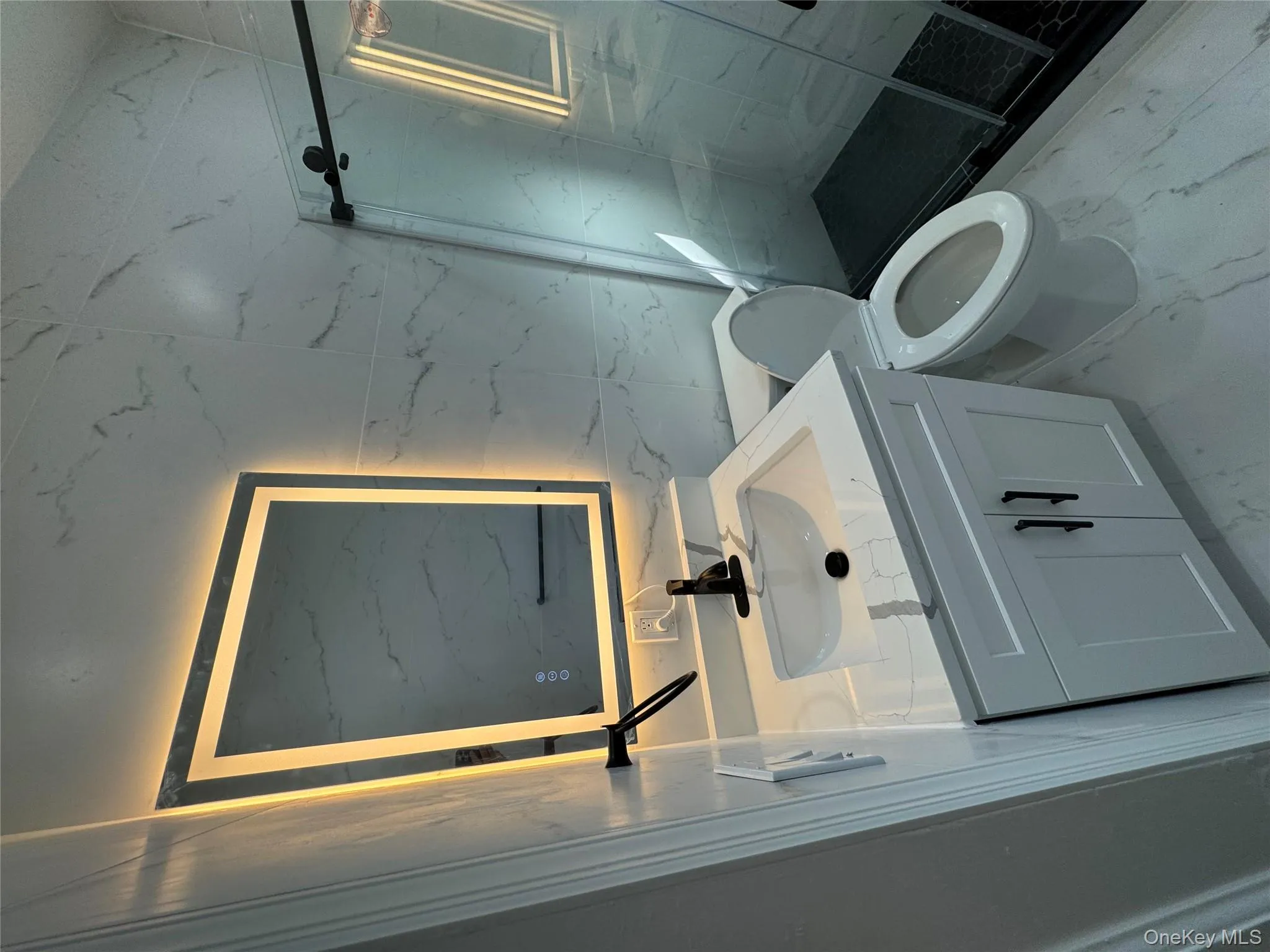 Bathroom with vanity, a marble finish shower, and light marble finish flooring Bathroom with vanity, a marble finish shower, and light marble finish flooring