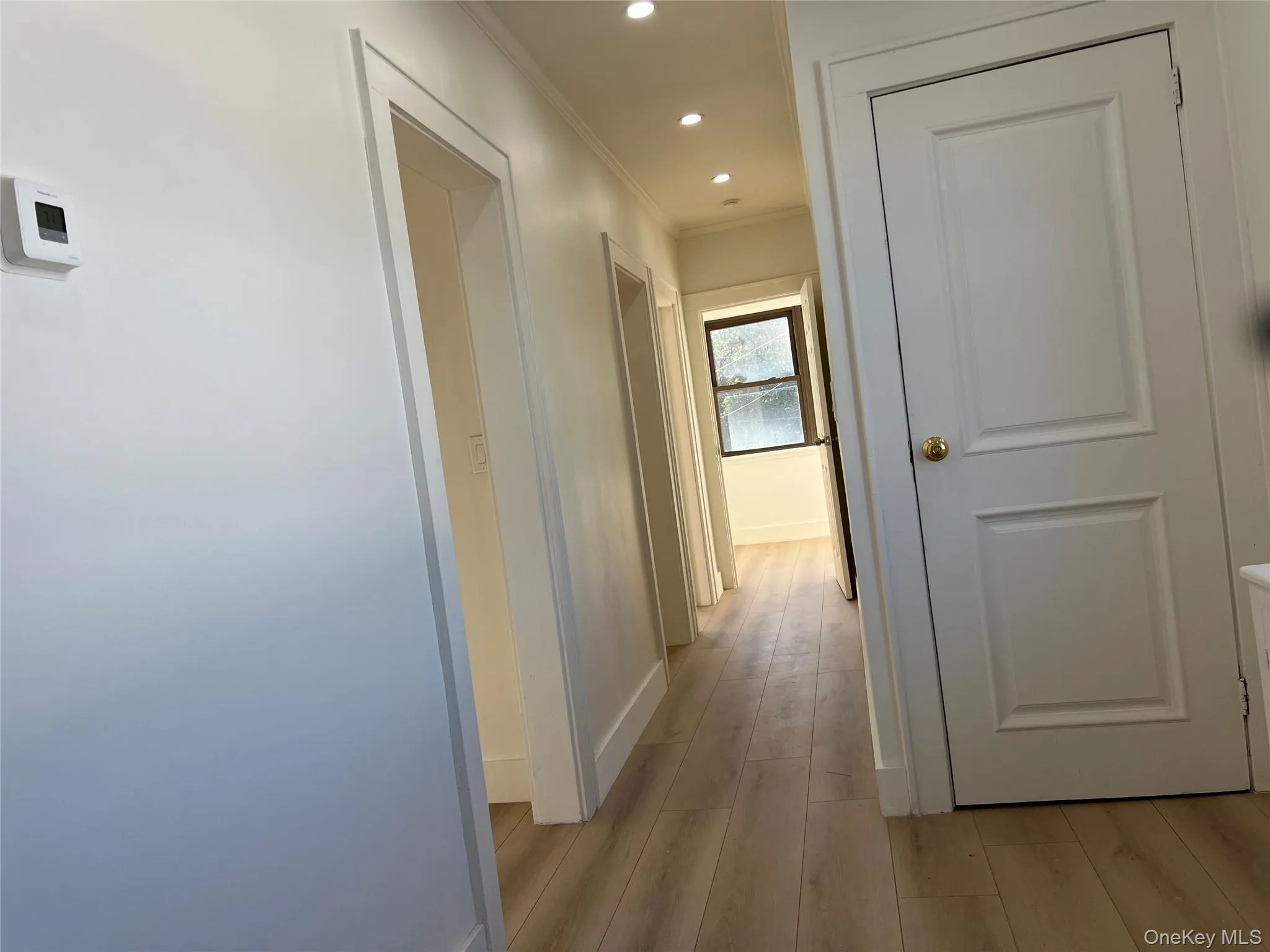 Hallway with light wood-style flooring, ornamental molding, and recessed lighting Hallway with light wood-style flooring, ornamental molding, and recessed lighting