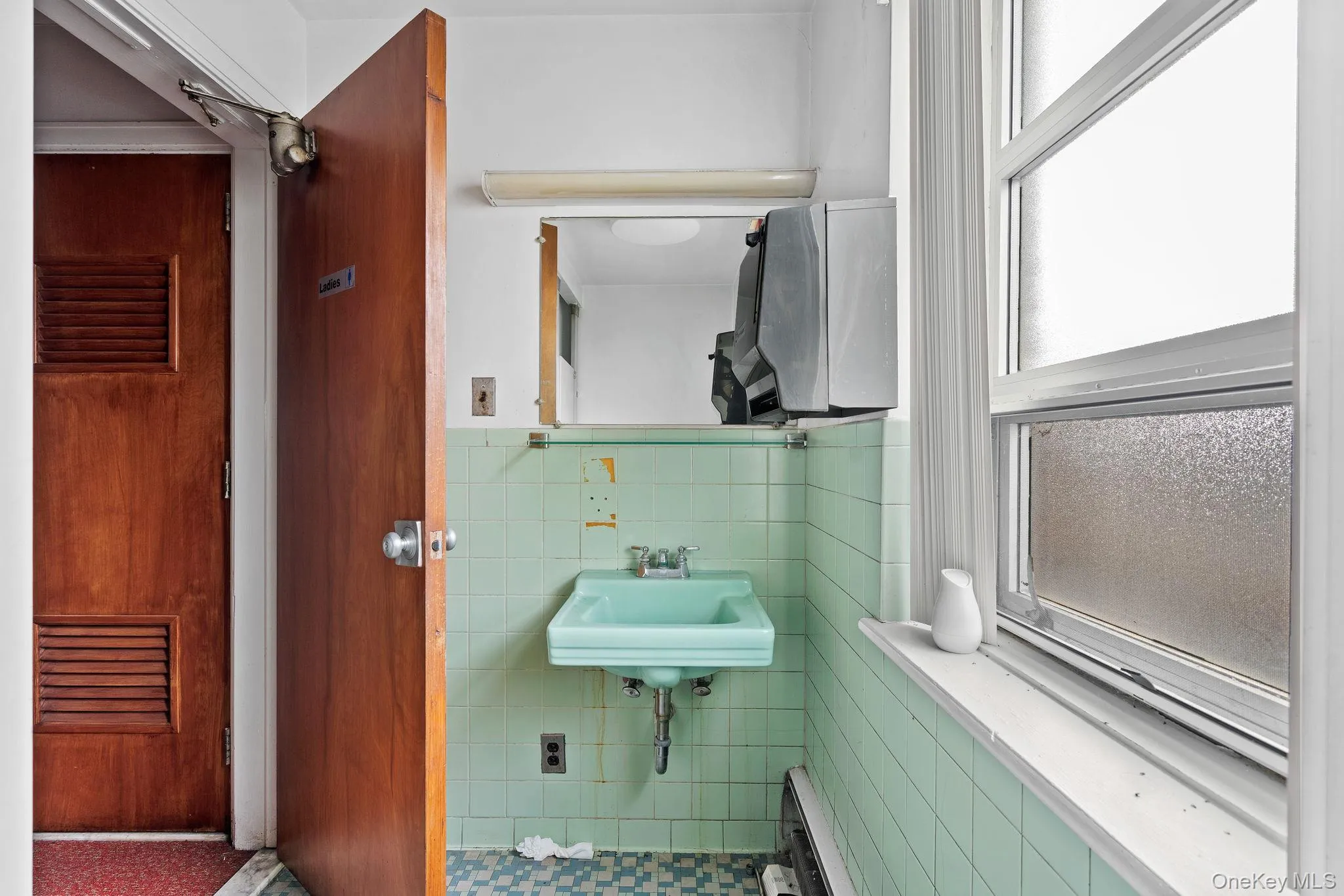 Half bath with tile walls, plenty of natural light, a baseboard heating unit, and wainscoting Half bath with tile walls, plenty of natural light, a baseboard heating unit, and wainscoting