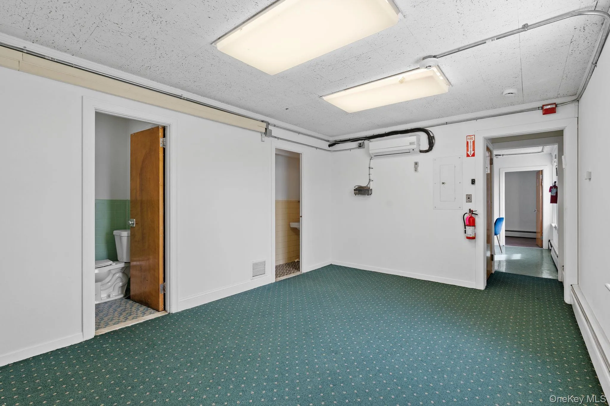 Basement with carpet, electric panel, and a wall unit AC Basement with carpet, electric panel, and a wall unit AC