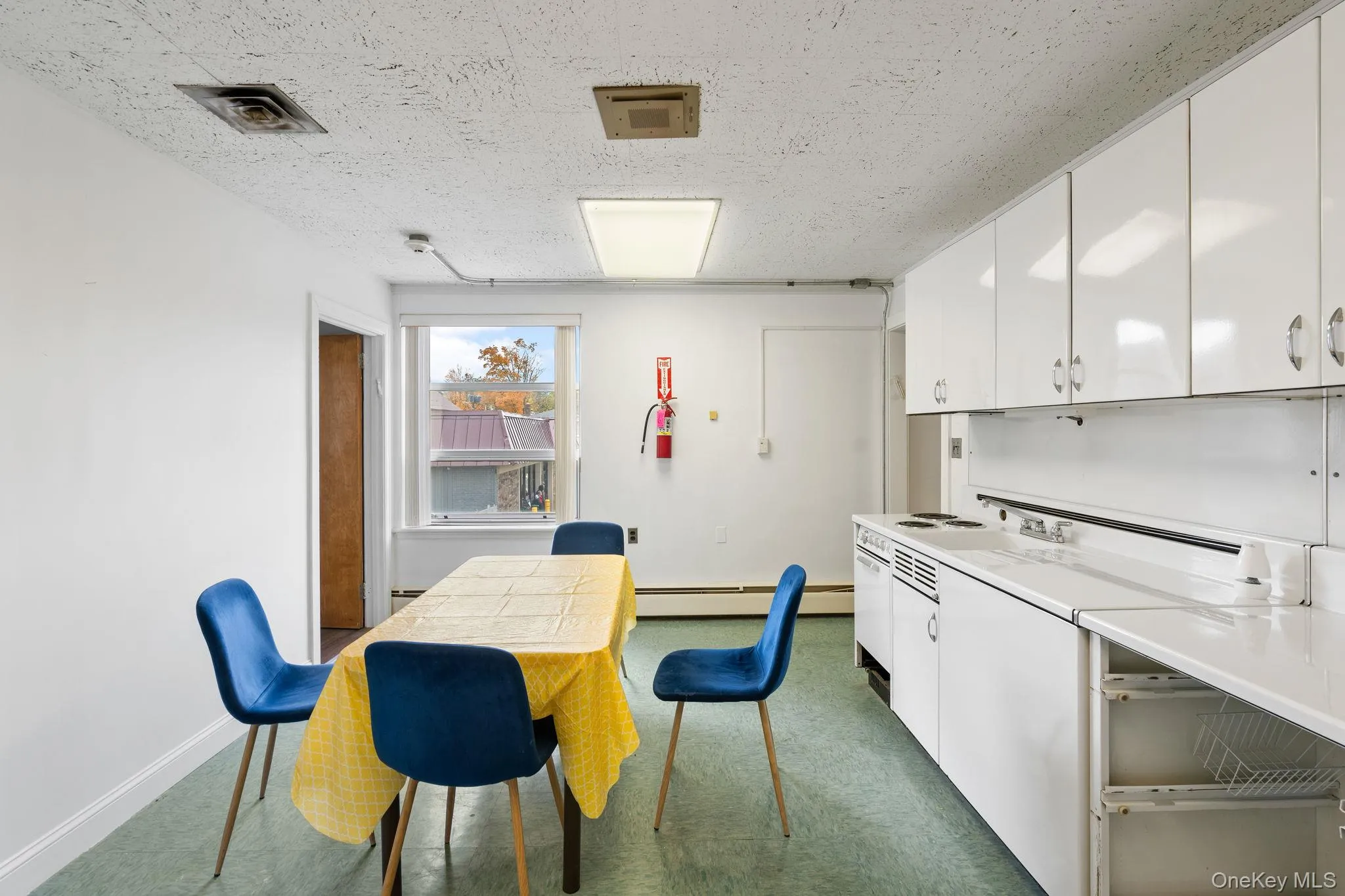 Kitchen featuring white cabinets, light countertops, a textured ceiling, white electric stove, and washer / dryer Kitchen featuring white cabinets, light countertops, a textured ceiling, white electric stove, and washer / dryer