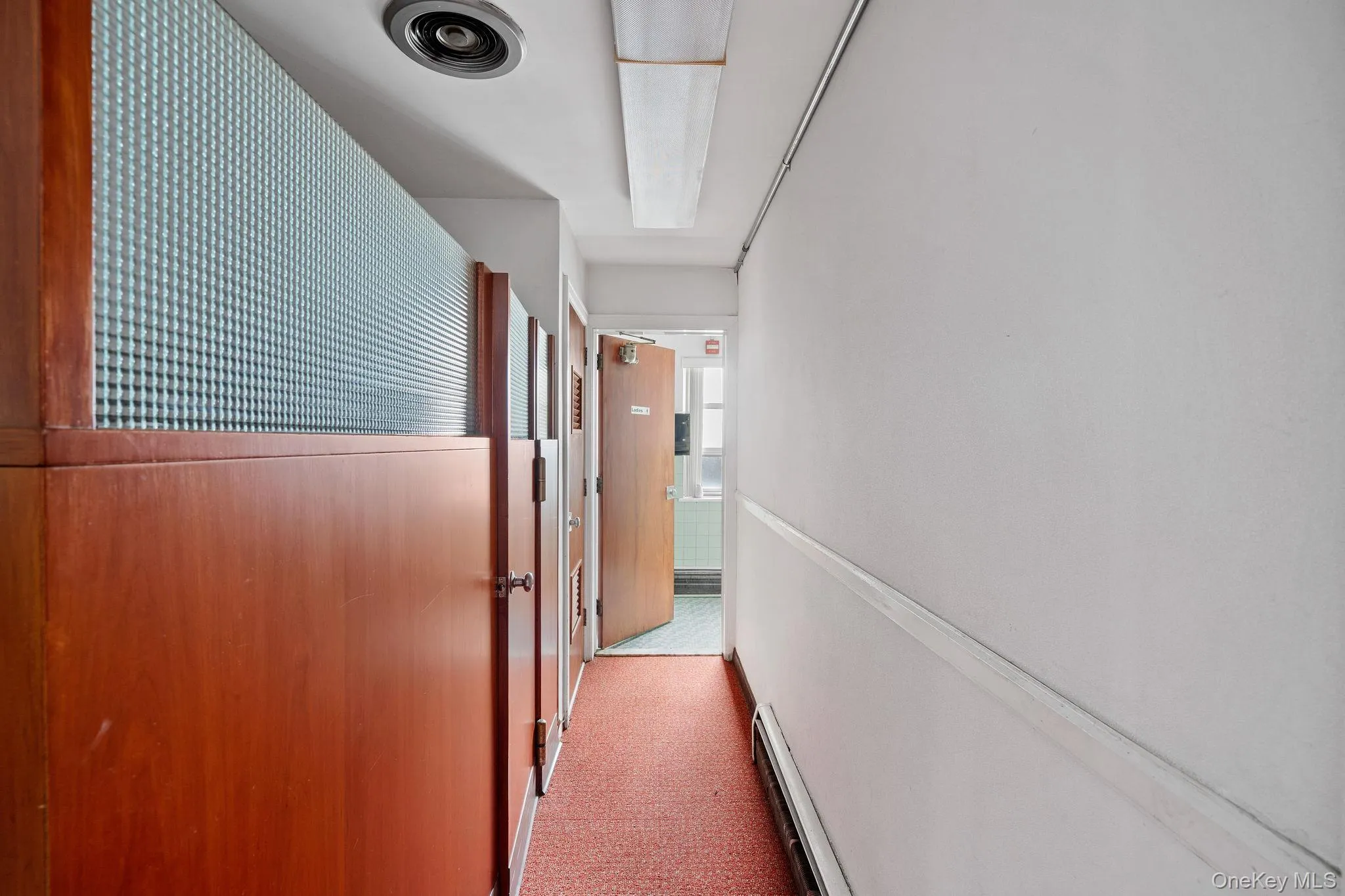 Hall featuring dark carpet and baseboard heating Hall featuring dark carpet and baseboard heating