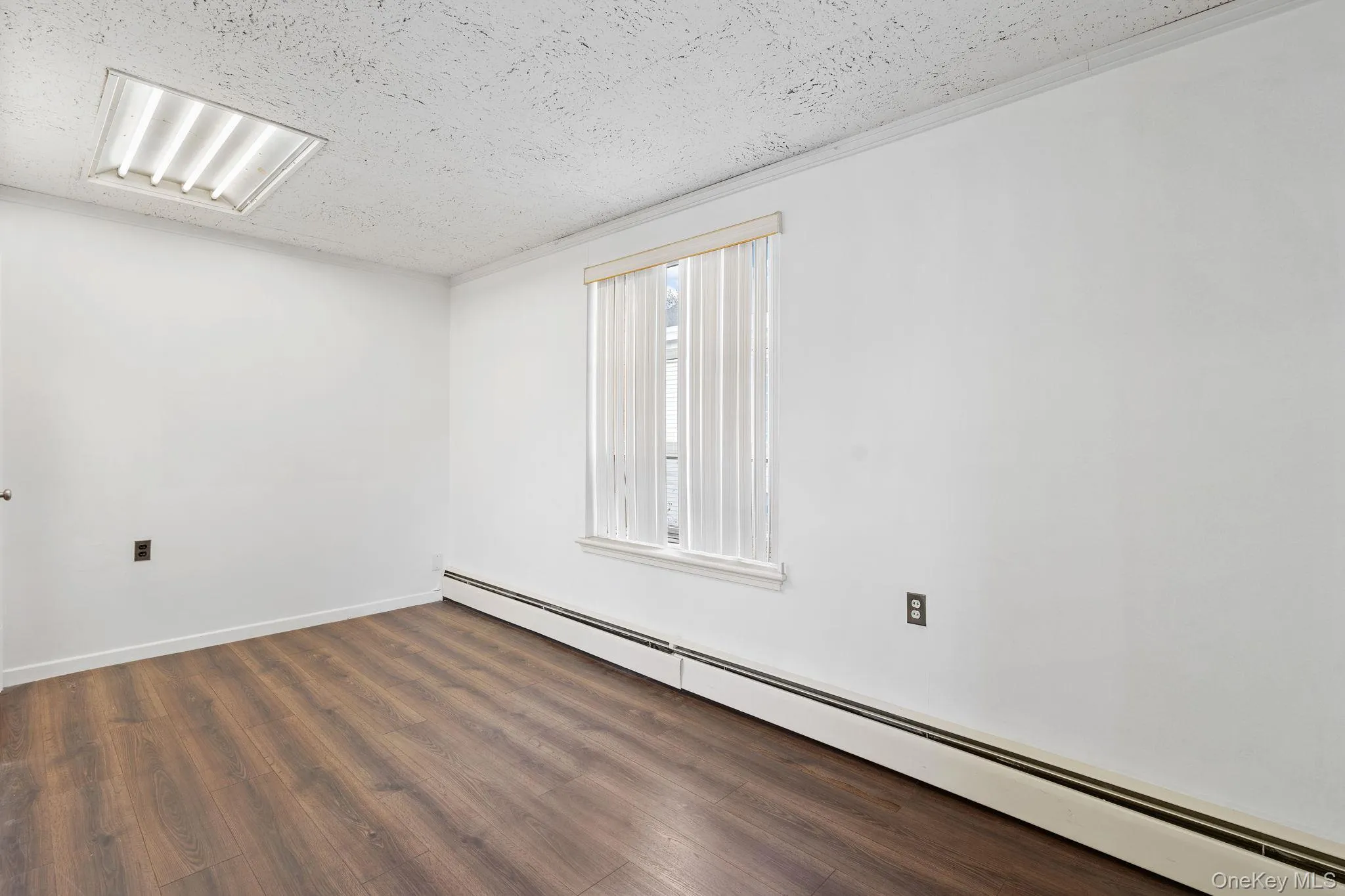 Spare room with baseboard heating, dark wood finished floors, and a textured ceiling Spare room with baseboard heating, dark wood finished floors, and a textured ceiling