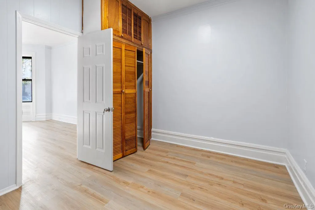 Unfurnished room with crown molding and light wood-style floors Unfurnished room with crown molding and light wood-style floors