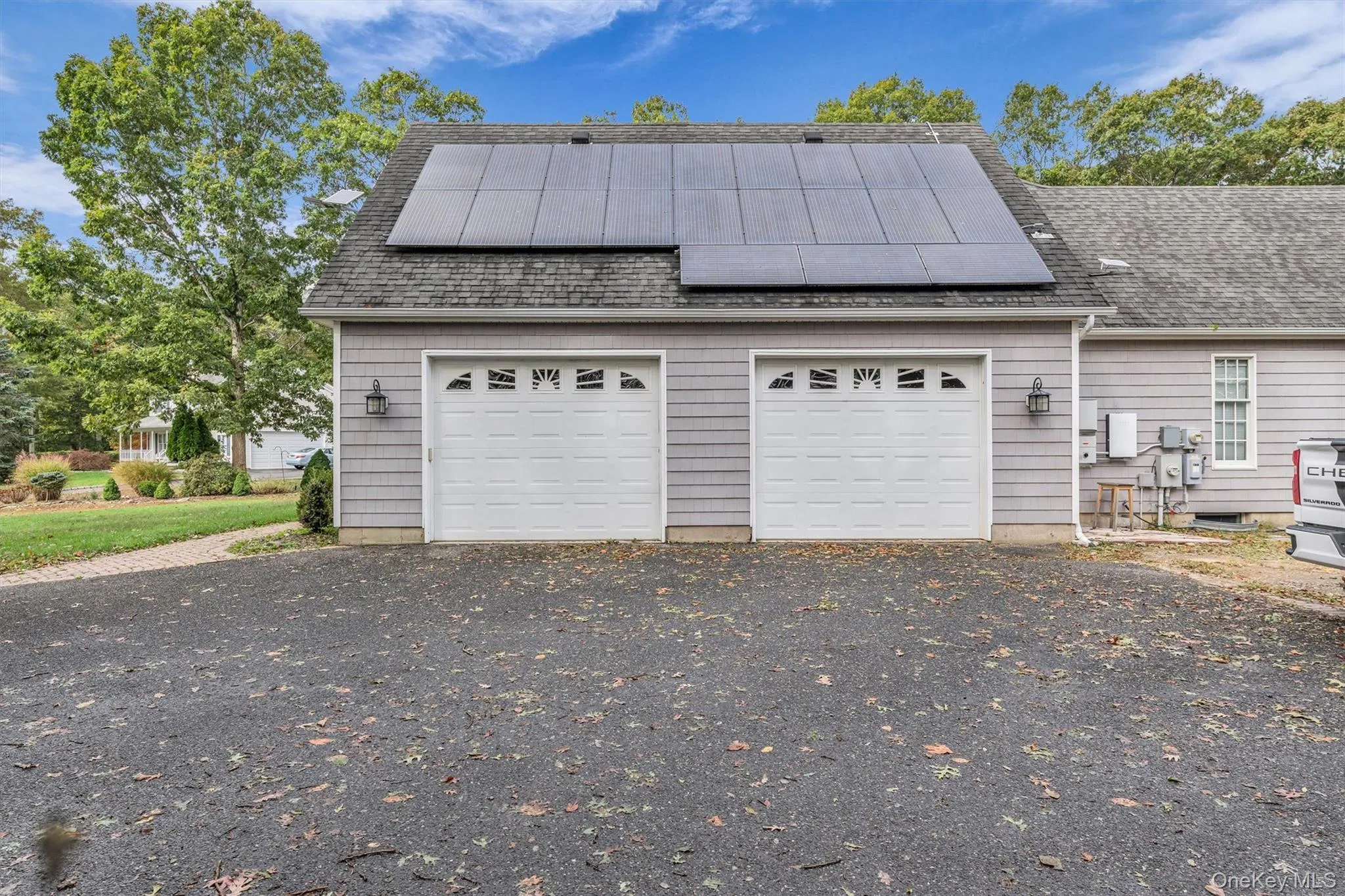 Garage featuring asphalt driveway and roof mounted solar panels Garage featuring asphalt driveway and roof mounted solar panels