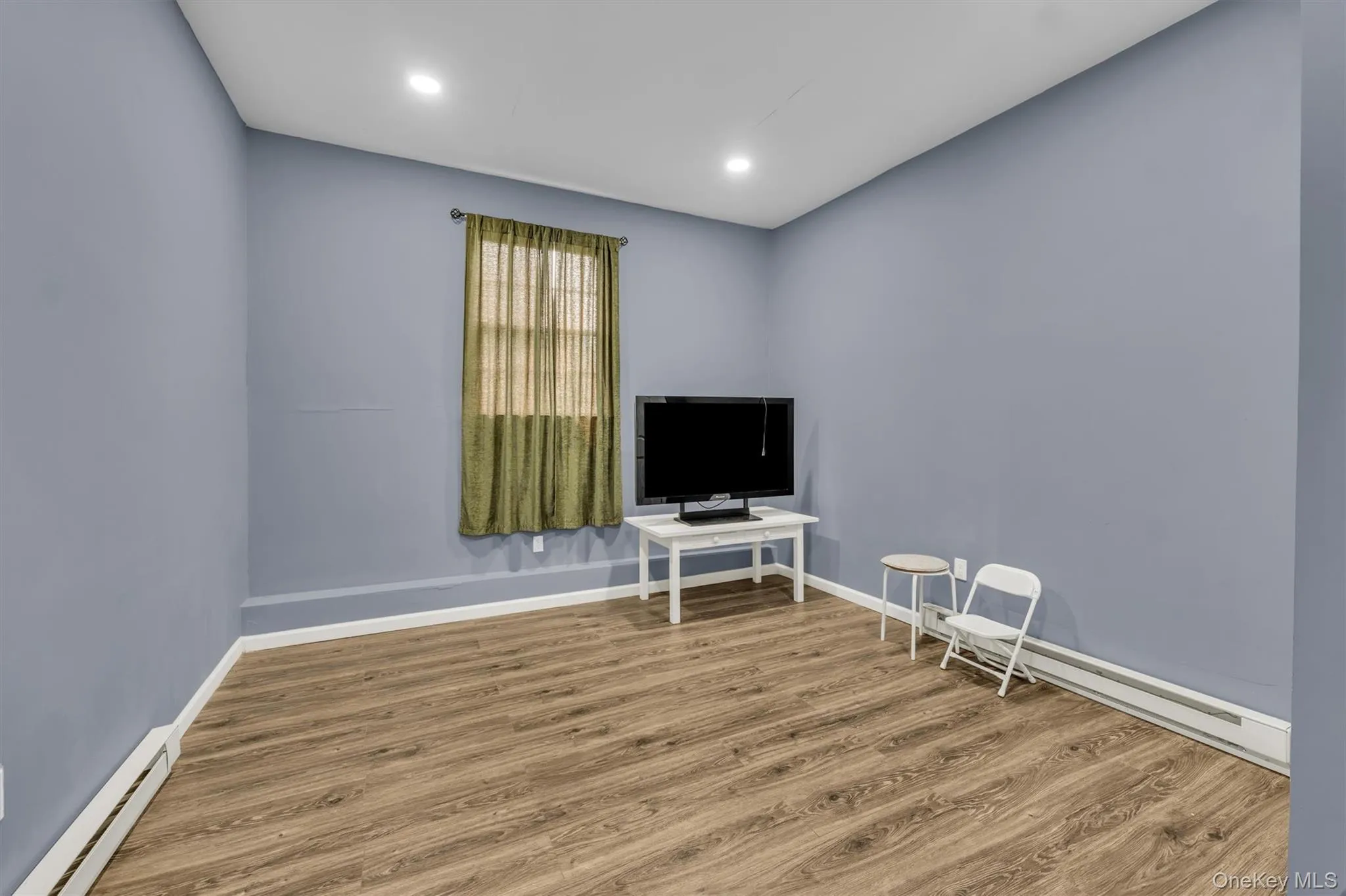 Living area featuring a baseboard heating unit, wood finished floors, and recessed lighting Living area featuring a baseboard heating unit, wood finished floors, and recessed lighting
