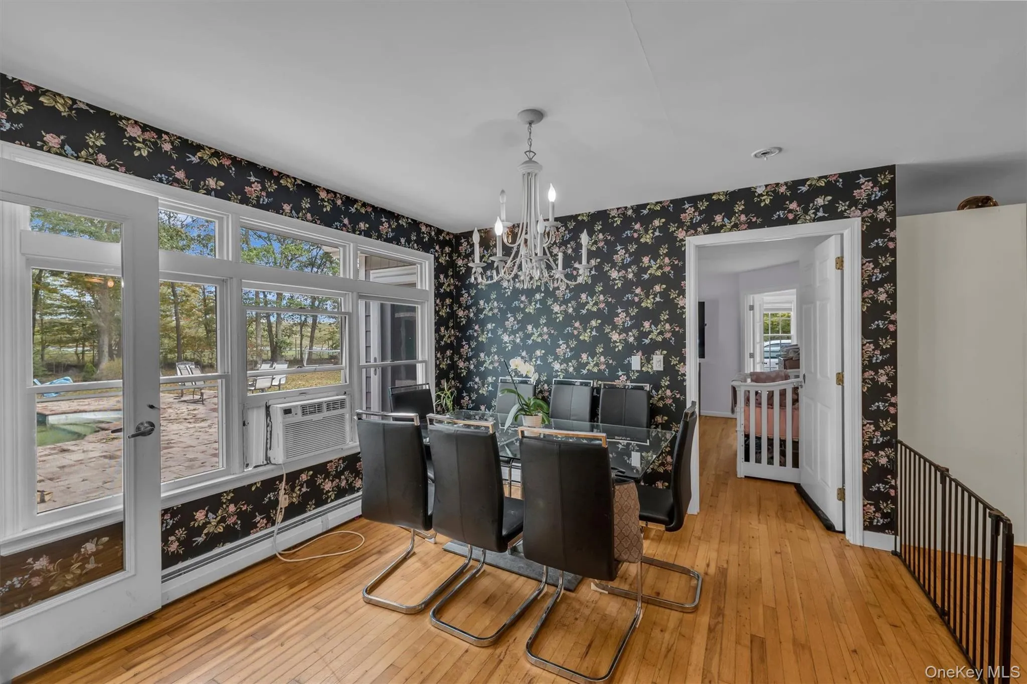 Dining space featuring wallpapered walls, a chandelier, light wood-style flooring, baseboard heating, and cooling unit Dining space featuring wallpapered walls, a chandelier, light wood-style flooring, baseboard heating, and cooling unit