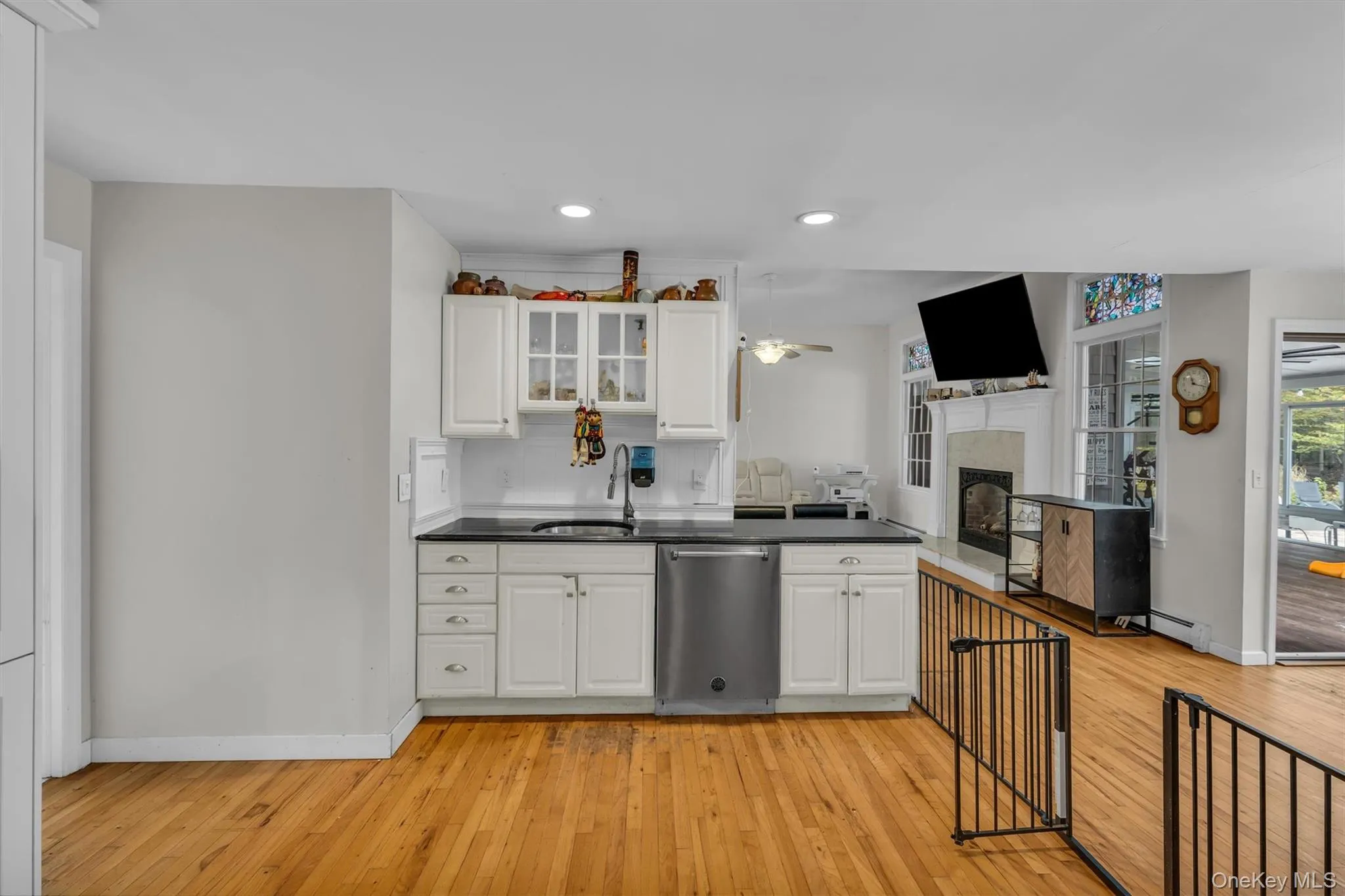 Kitchen with recessed lighting, dishwasher, white cabinets, a fireplace, and light wood-style flooring Kitchen with recessed lighting, dishwasher, white cabinets, a fireplace, and light wood-style flooring