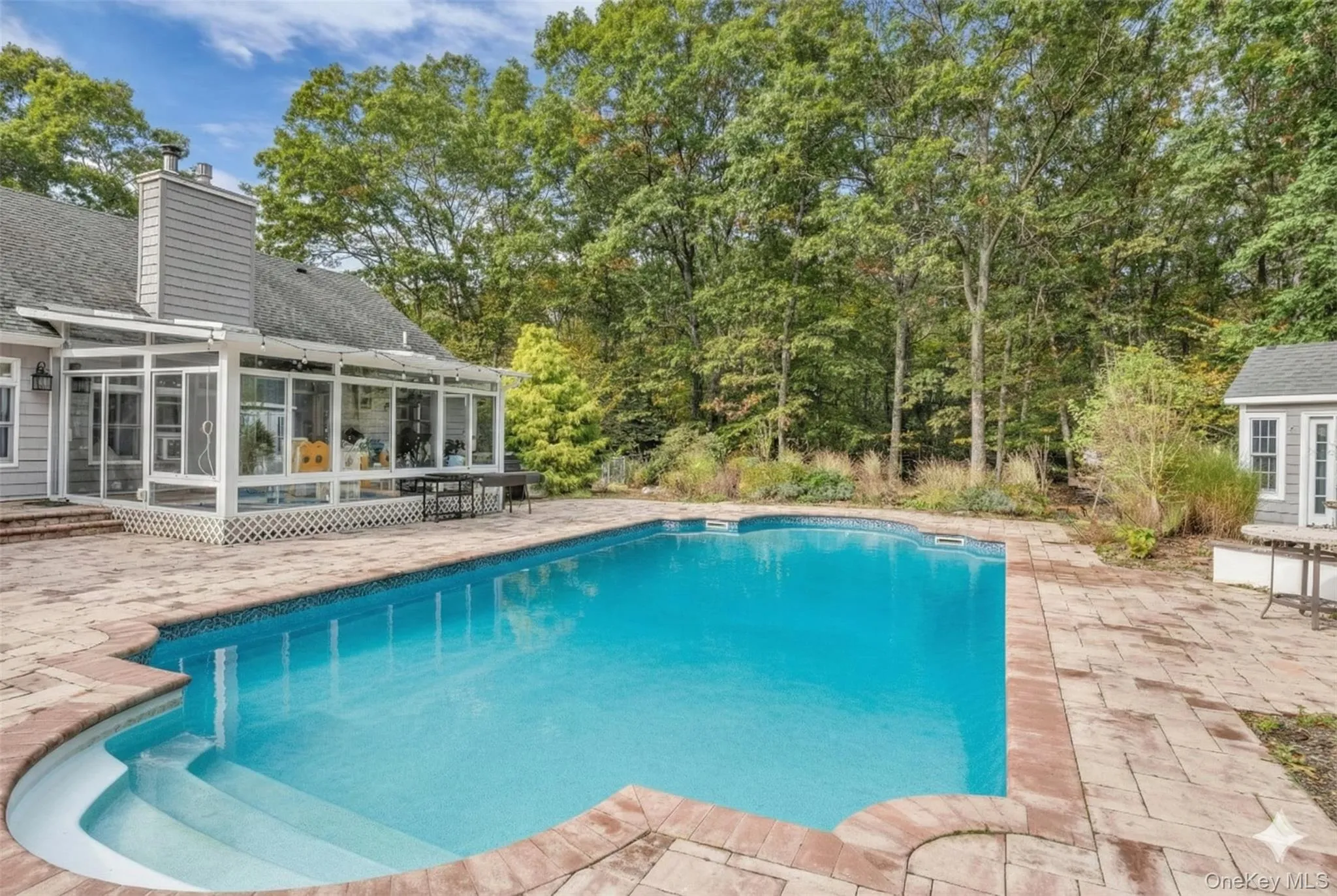 Outdoor pool with a patio, a sunroom, and an outdoor structure Outdoor pool with a patio, a sunroom, and an outdoor structure