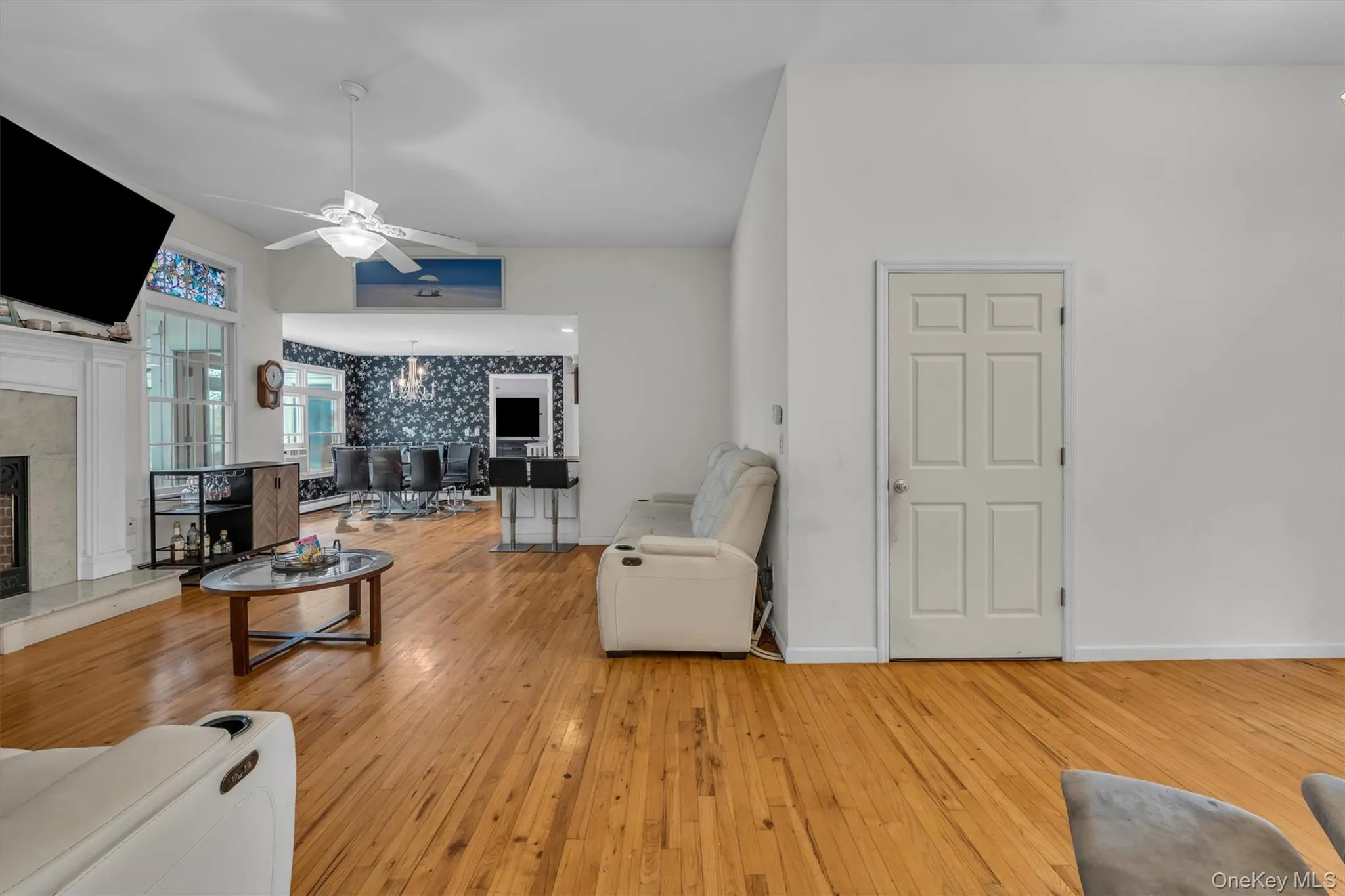 Living area with a chandelier, a fireplace, light wood-type flooring, ceiling fan, and lofted ceiling Living area with a chandelier, a fireplace, light wood-type flooring, ceiling fan, and lofted ceiling