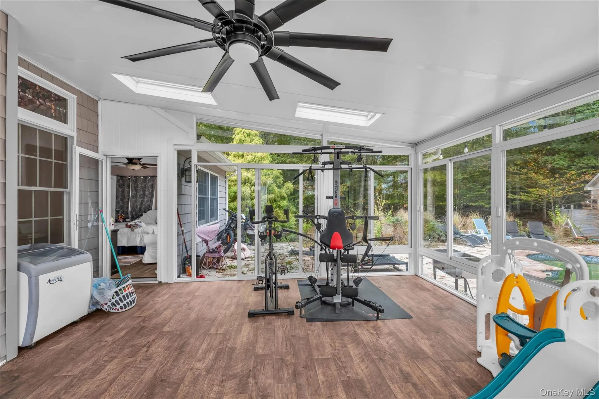 Exercise area with expansive windows, wood finished floors, a skylight, a ceiling fan, and lofted ceiling Exercise area with expansive windows, wood finished floors, a skylight, a ceiling fan, and lofted ceiling