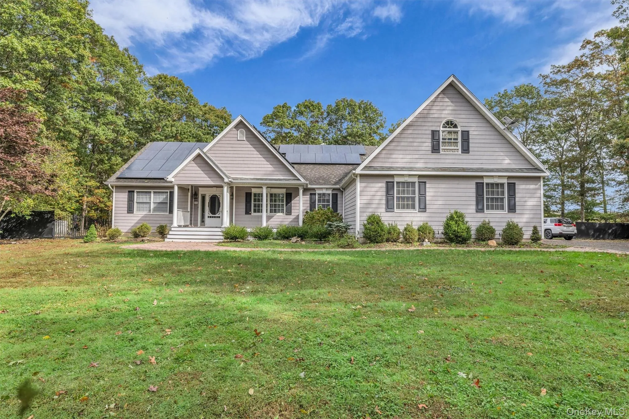 View of front of home with covered porch, a front lawn, and solar panels View of front of home with covered porch, a front lawn, and solar panels