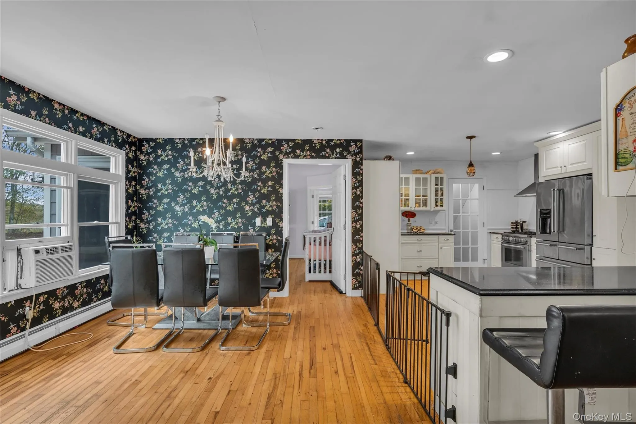Kitchen with wallpapered walls, dark countertops, premium appliances, light wood finished floors, and white cabinetry Kitchen with wallpapered walls, dark countertops, premium appliances, light wood finished floors, and white cabinetry