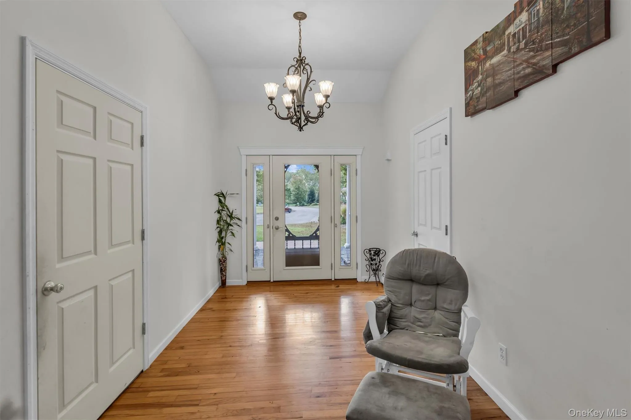 Entrance foyer featuring wood finished floors, a chandelier, and vaulted ceiling Entrance foyer featuring wood finished floors, a chandelier, and vaulted ceiling