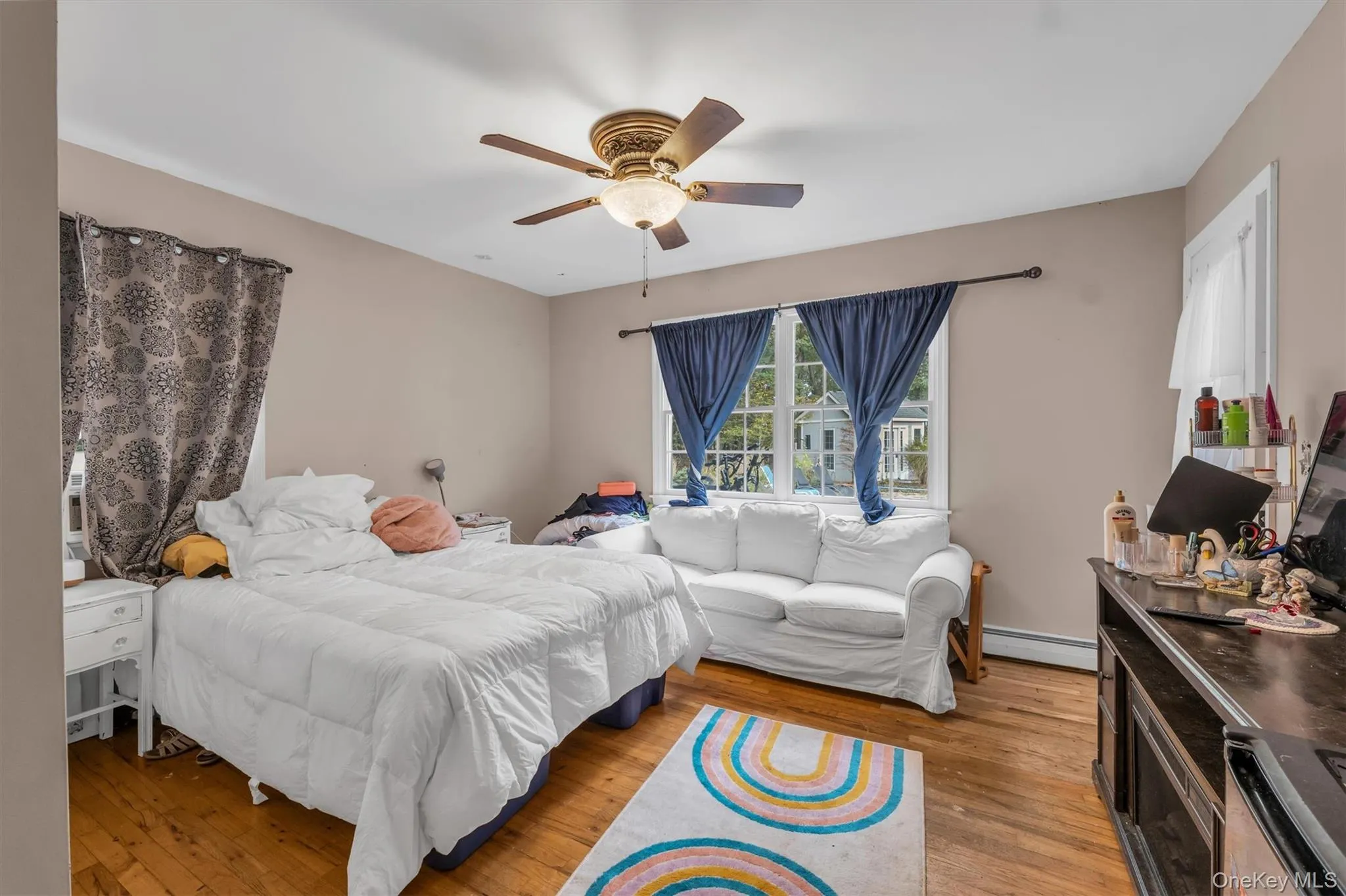 Bedroom with light wood-style flooring, a ceiling fan, and a baseboard radiator Bedroom with light wood-style flooring, a ceiling fan, and a baseboard radiator