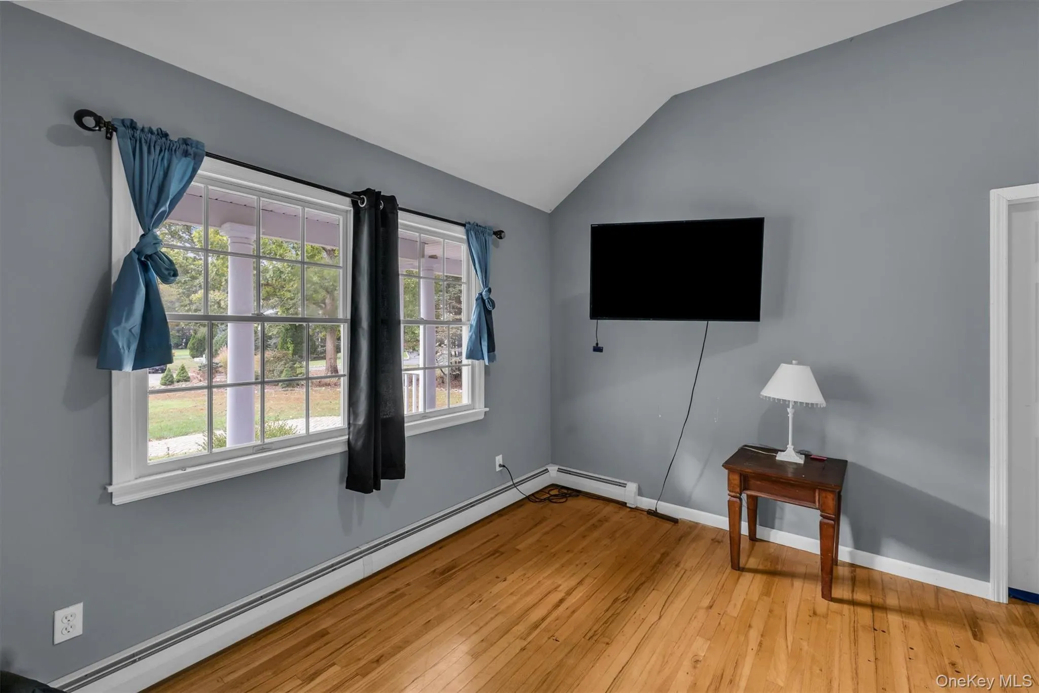 Unfurnished bedroom featuring baseboard heating, vaulted ceiling, and light wood-style flooring Unfurnished bedroom featuring baseboard heating, vaulted ceiling, and light wood-style flooring