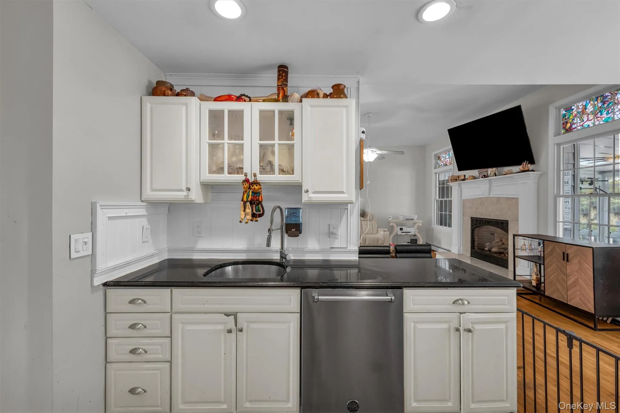 Kitchen featuring stainless steel dishwasher, open floor plan, white cabinets, dark stone counters, and recessed lighting Kitchen featuring stainless steel dishwasher, open floor plan, white cabinets, dark stone counters, and recessed lighting