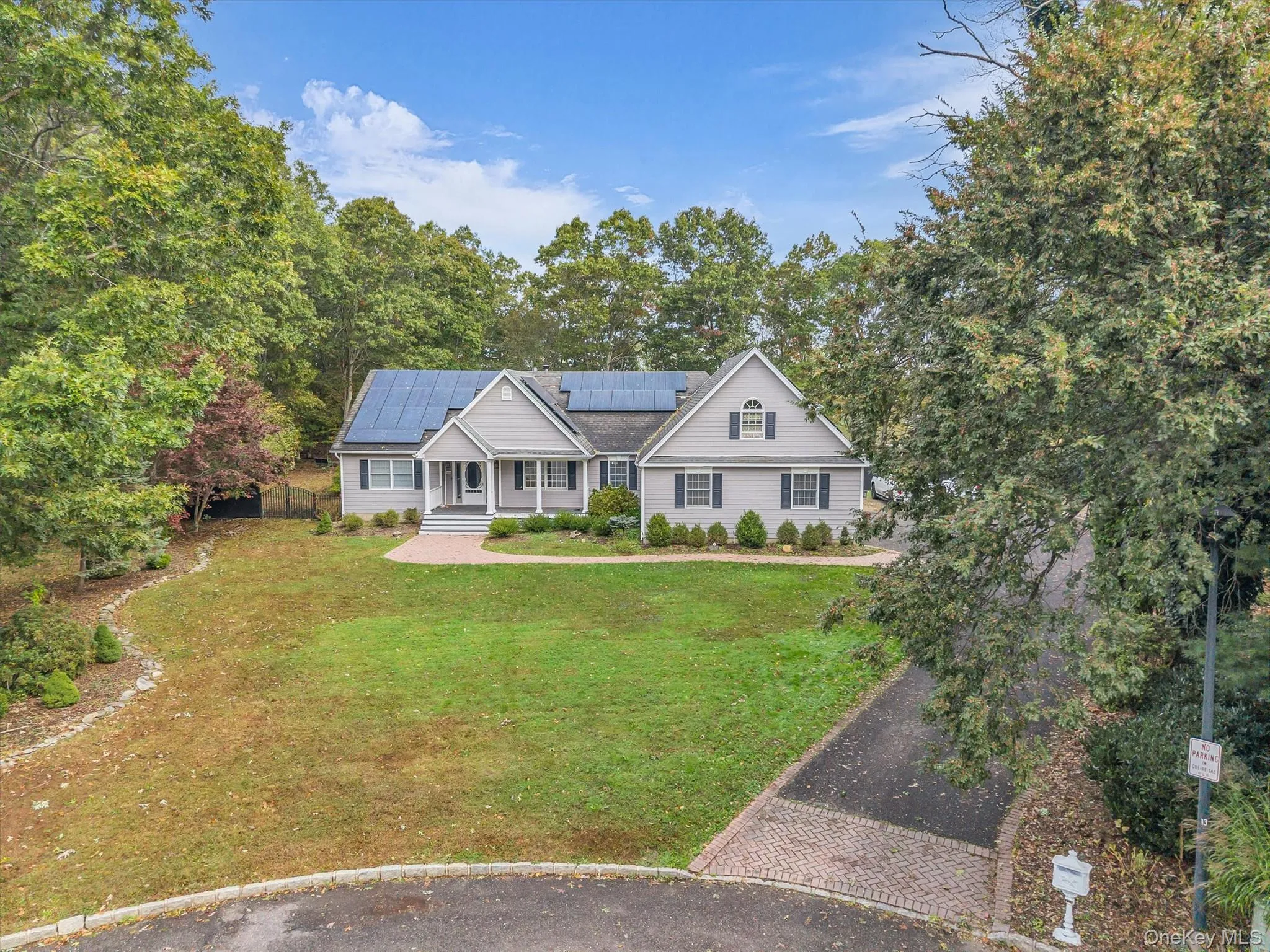 Traditional-style house with a front lawn, solar panels, and view of wooded area Traditional-style house with a front lawn, solar panels, and view of wooded area