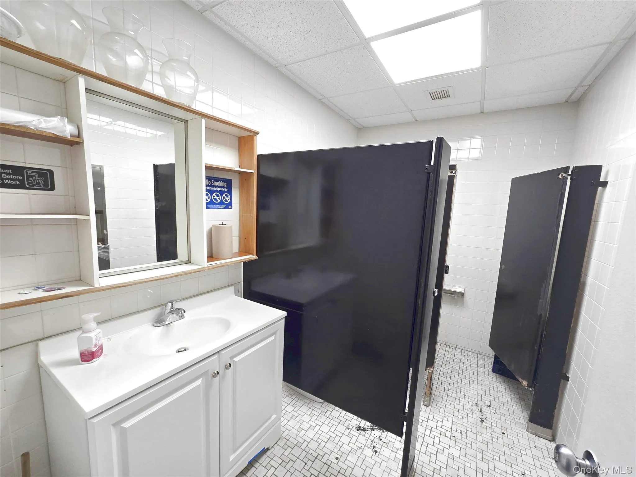 Bathroom with tile walls, vanity, and a paneled ceiling Bathroom with tile walls, vanity, and a paneled ceiling